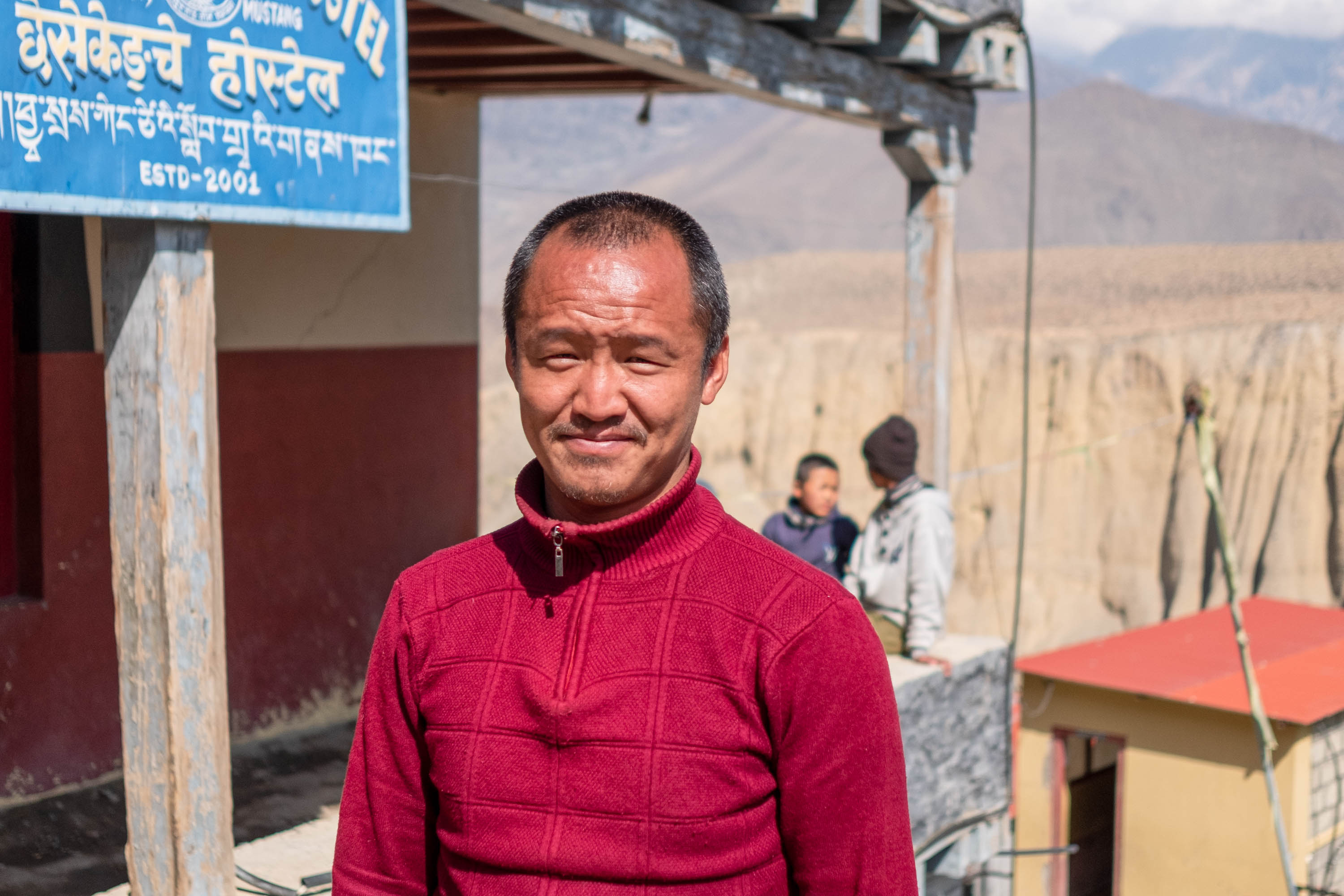 Nyima Dhundul Gurung, a Bon monk from Lubra, stands outside the Chasey Kengtse Hostel, which he runs [Eileen McDougall/Al Jazeera]