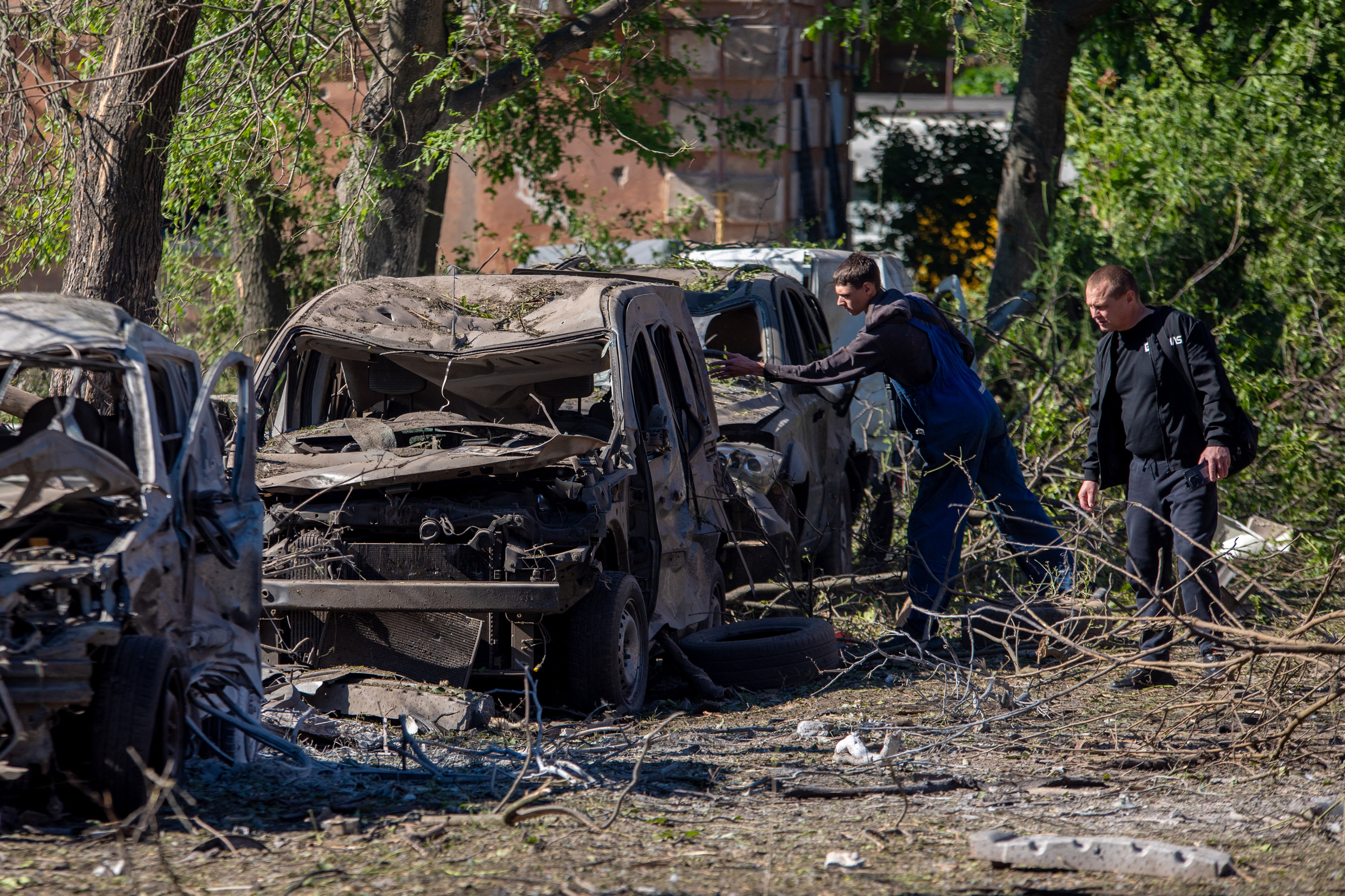 Two men inspect destroyed cars at the site of an air attack in Dnipro on June 2, 2026, amid the Russian invasion of Ukraine.