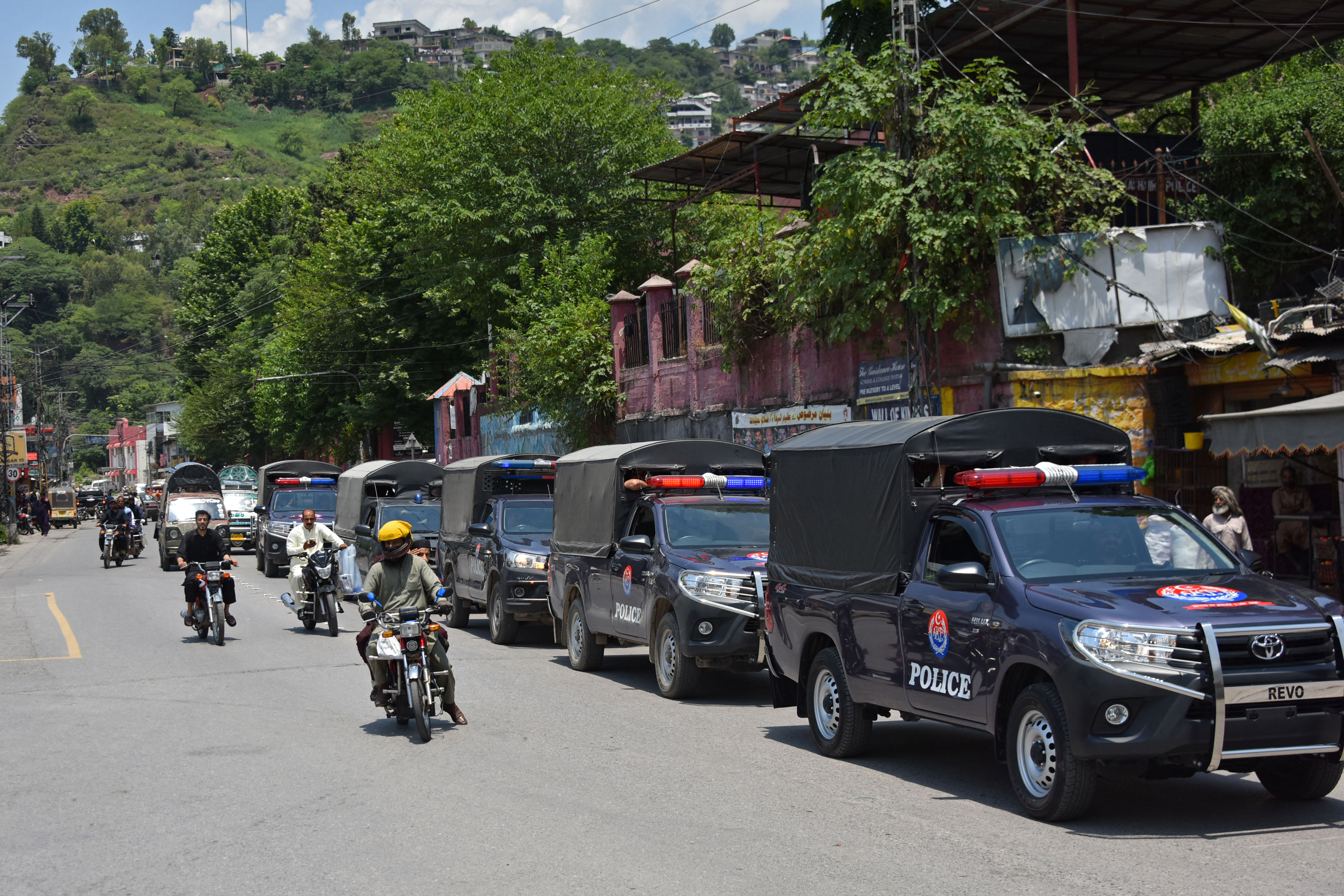 Commuters ride past security personnel in a street.