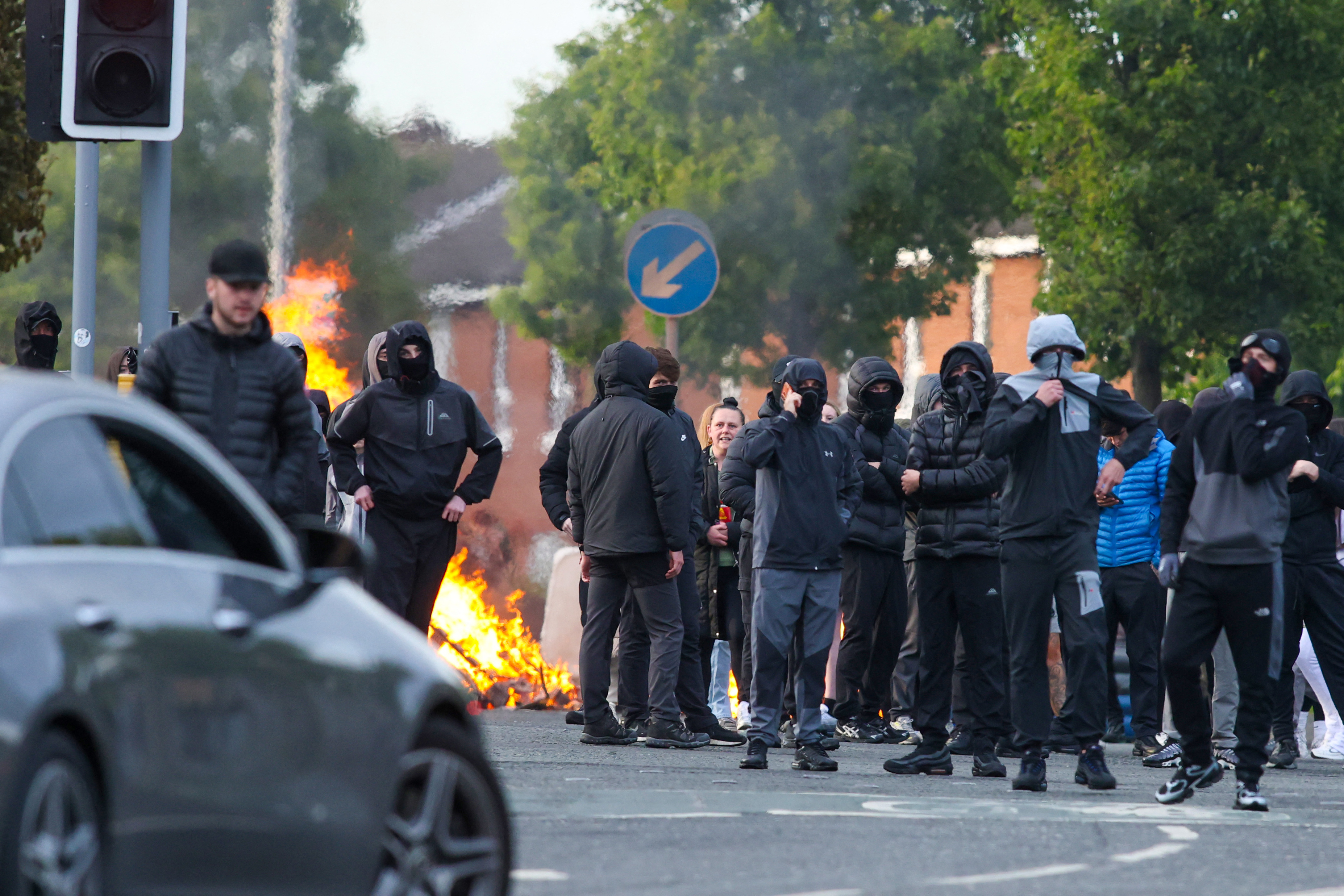 Masked youths block a road with burning debris in north Belfast, Northern Ireland, in the evening of June 9, 2026.
