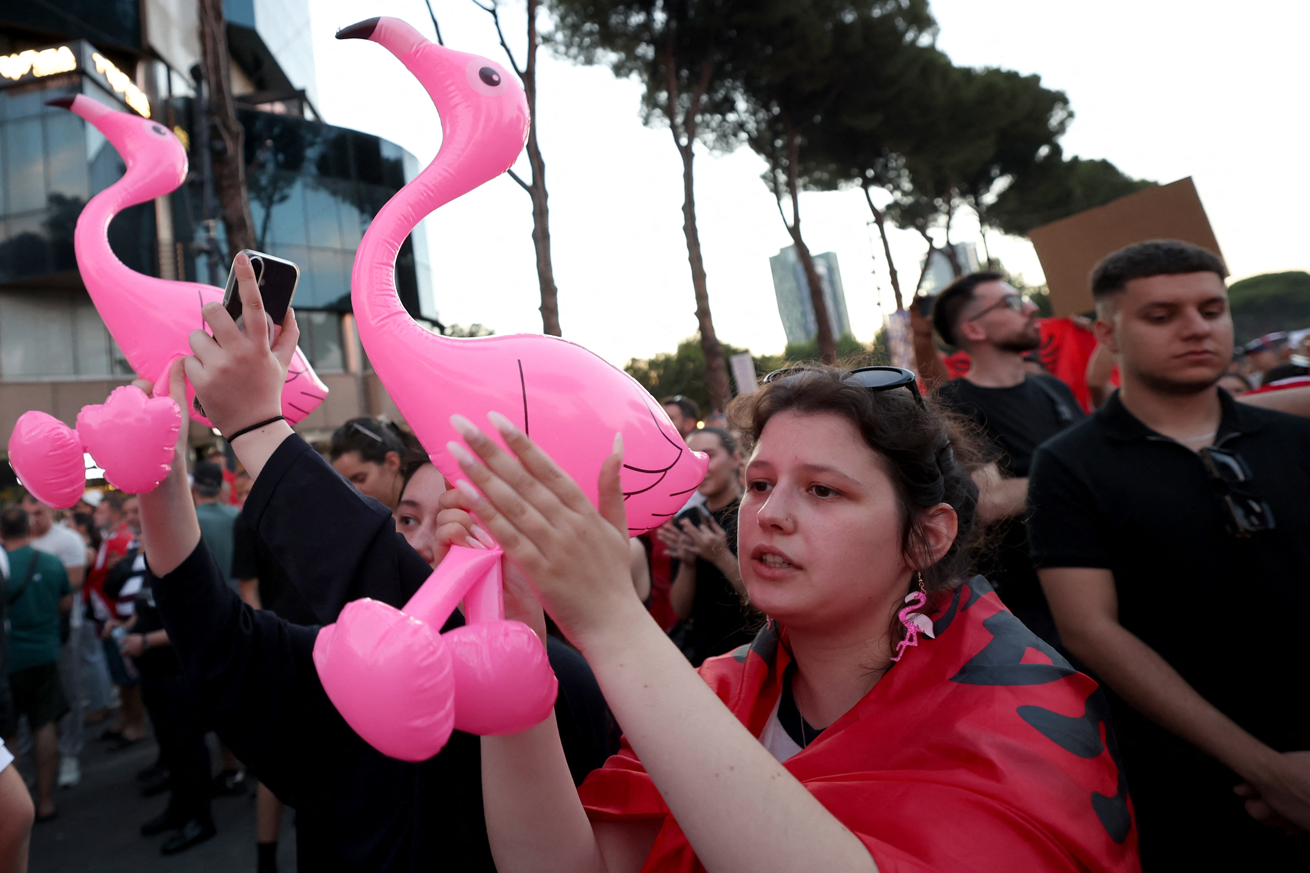 Protestors hold inflatable flamingos as they gather in front of the Albanian Prime Minister's Office to demonstrate against the construction on the southern coast of Albania of a luxury resort near a protected natural area, in Tirana, on June 10, 2026.