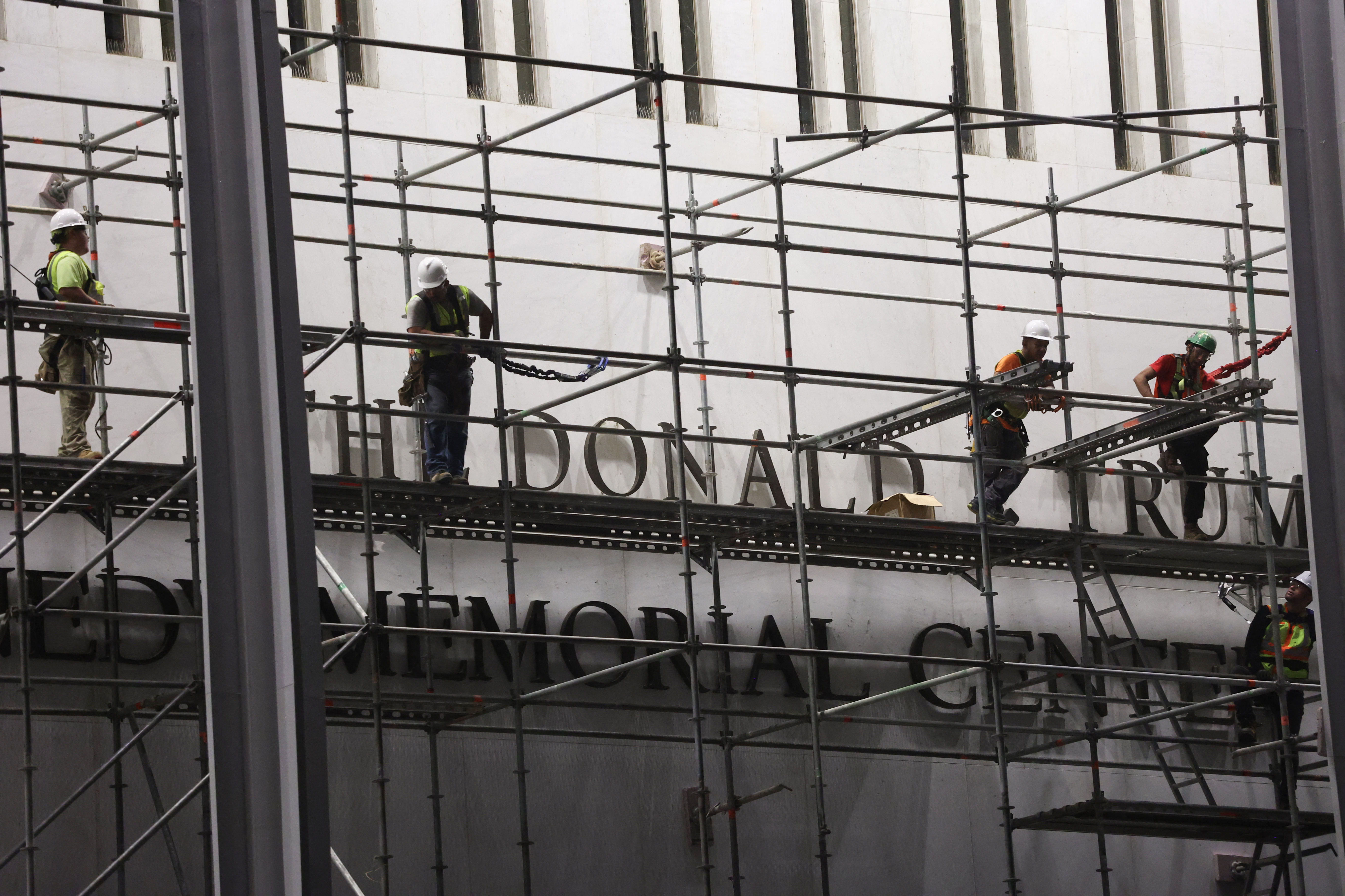 Workers build scaffolding near the signage for the "Donald J. Trump and John F. Kennedy Memorial Center for the Performing Arts" in Washington, DC, early on June 13, 2026.