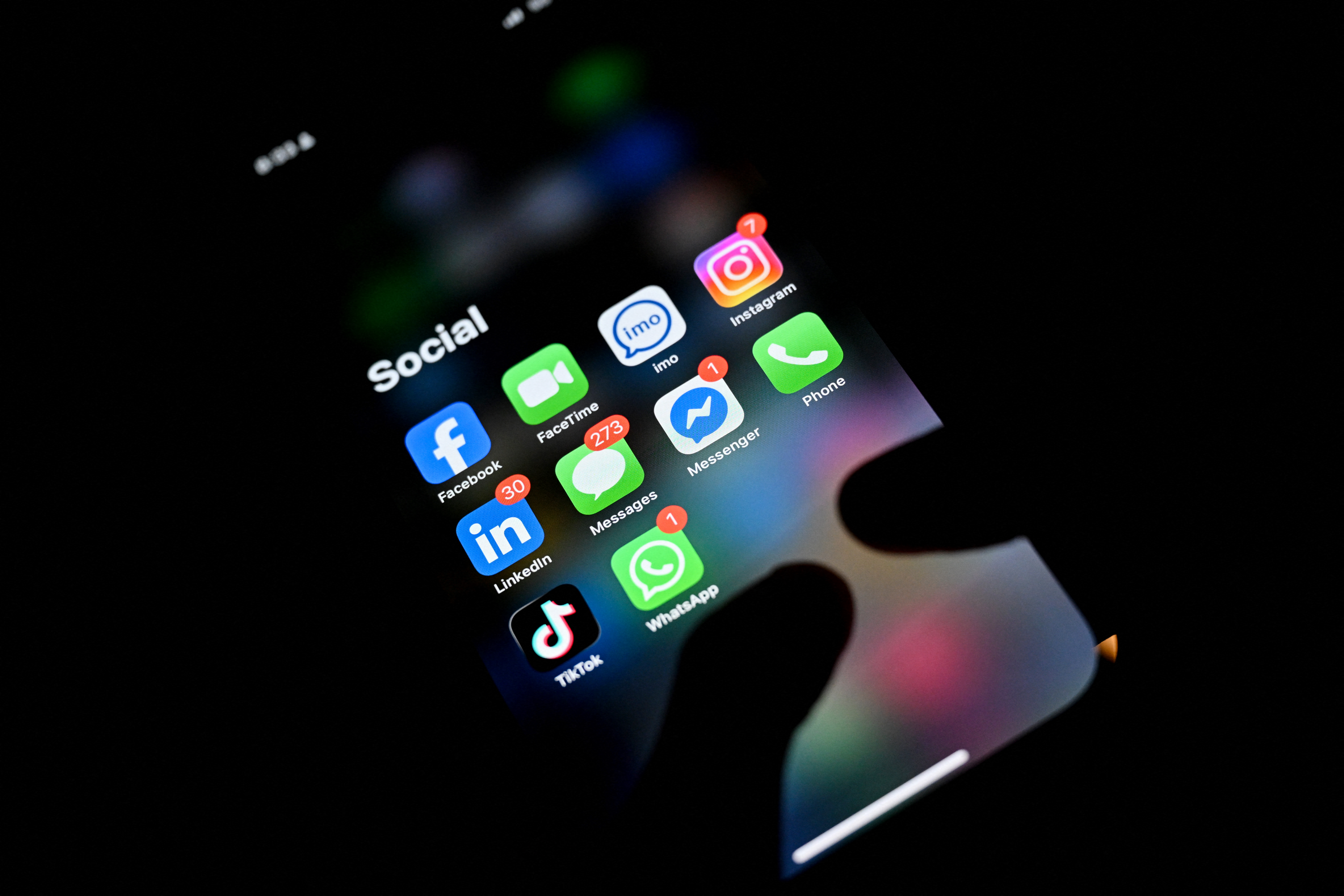 A man uses a smartphone as various social media apps are displayed on screen in Pugoda on June 12, 2026.