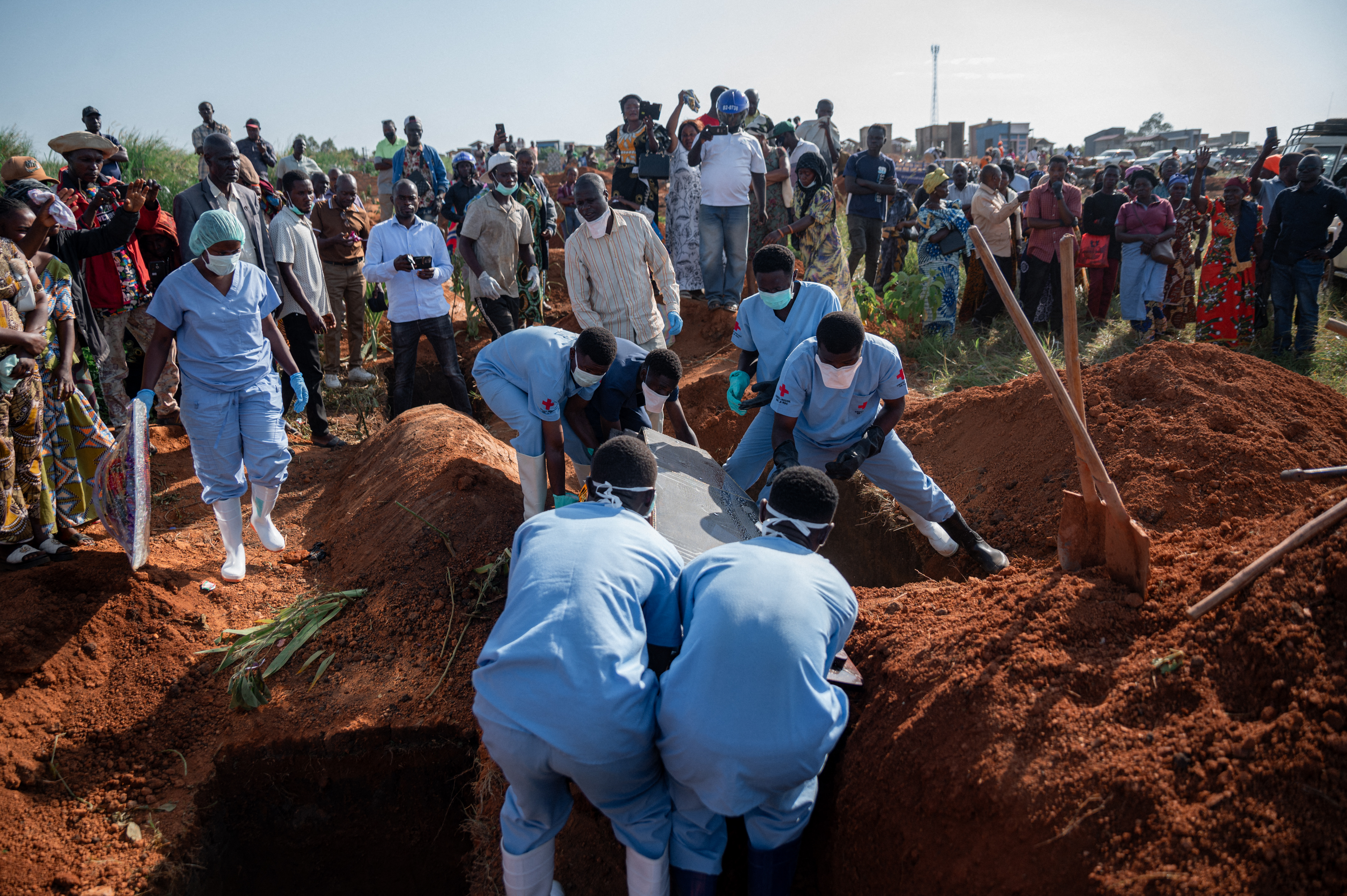 Family members and a group of midwives cry upon the arrival at the cemetery of the casket containing the body of their relative, who died from Ebola, as it is lowered into a grave in Bunia, Ituri Province, Democratic Republic of the Congo