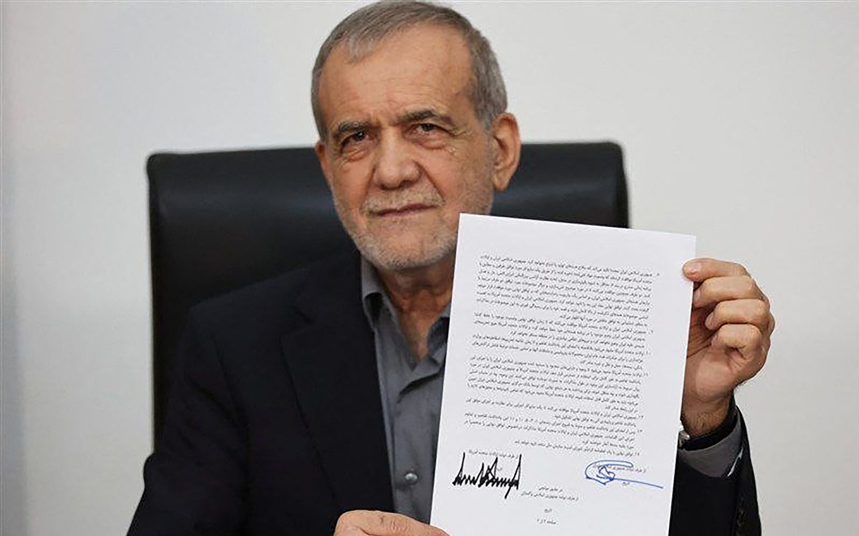 TOPSHOT - This handout from the Telegram account of the Islamic Republic of Iran Broadcasting (IRIB) on June 18, 2026 shows Iran's President Masoud Pezeshkian holding a document showing a memorandum of understanding he signed to end the Middle East war.