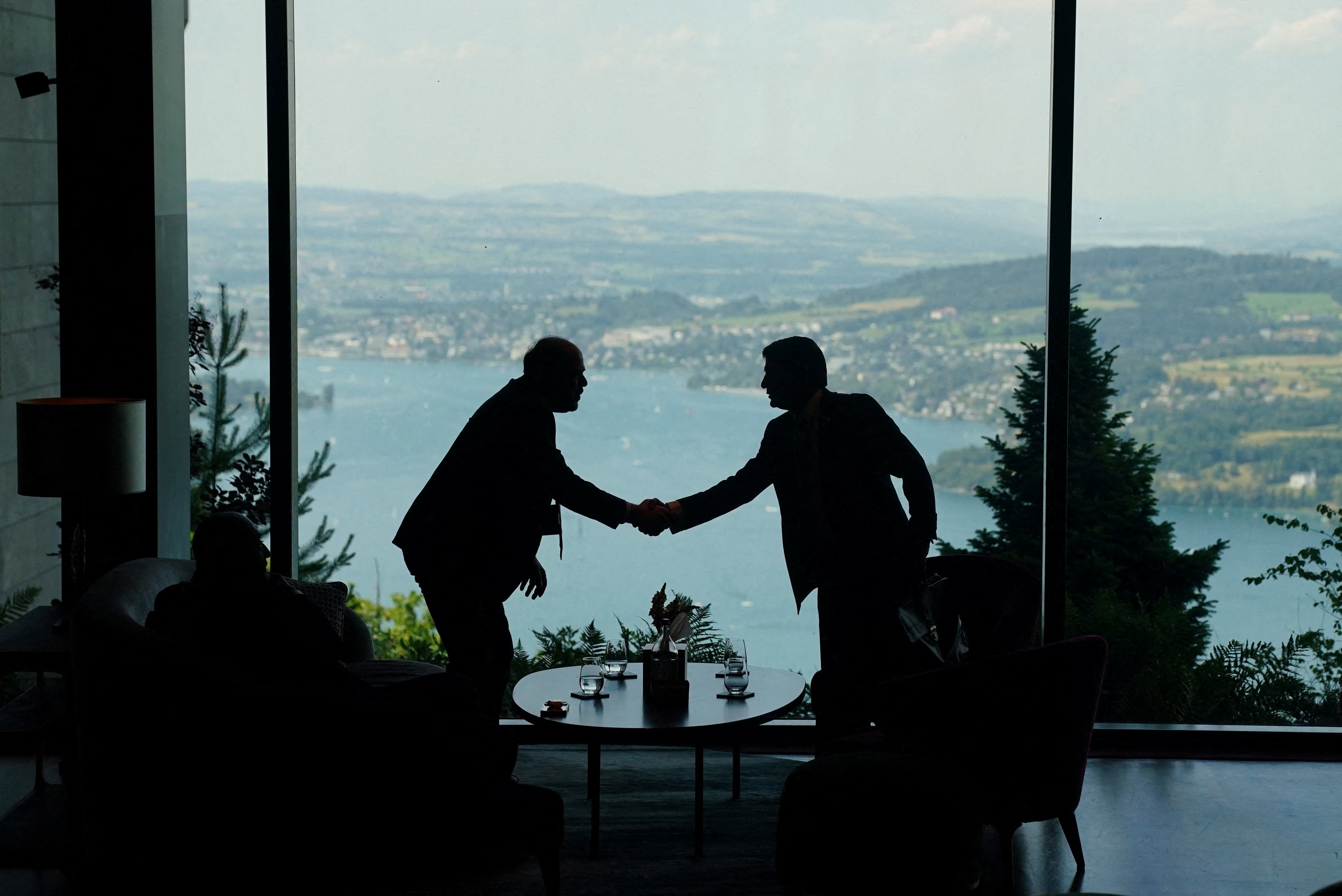 TOPSHOT - Delegation staff members meet in the lobby on the day of a quadrilateral meeting between the United States, Iran, Pakistan and Qatar at the Burgenstock luxury hotel complex overlooking Lake Lucerne, Switzerland, on June 21, 2026, as part of high-level talks aimed at advancing a deal to end the Middle East conflict.
