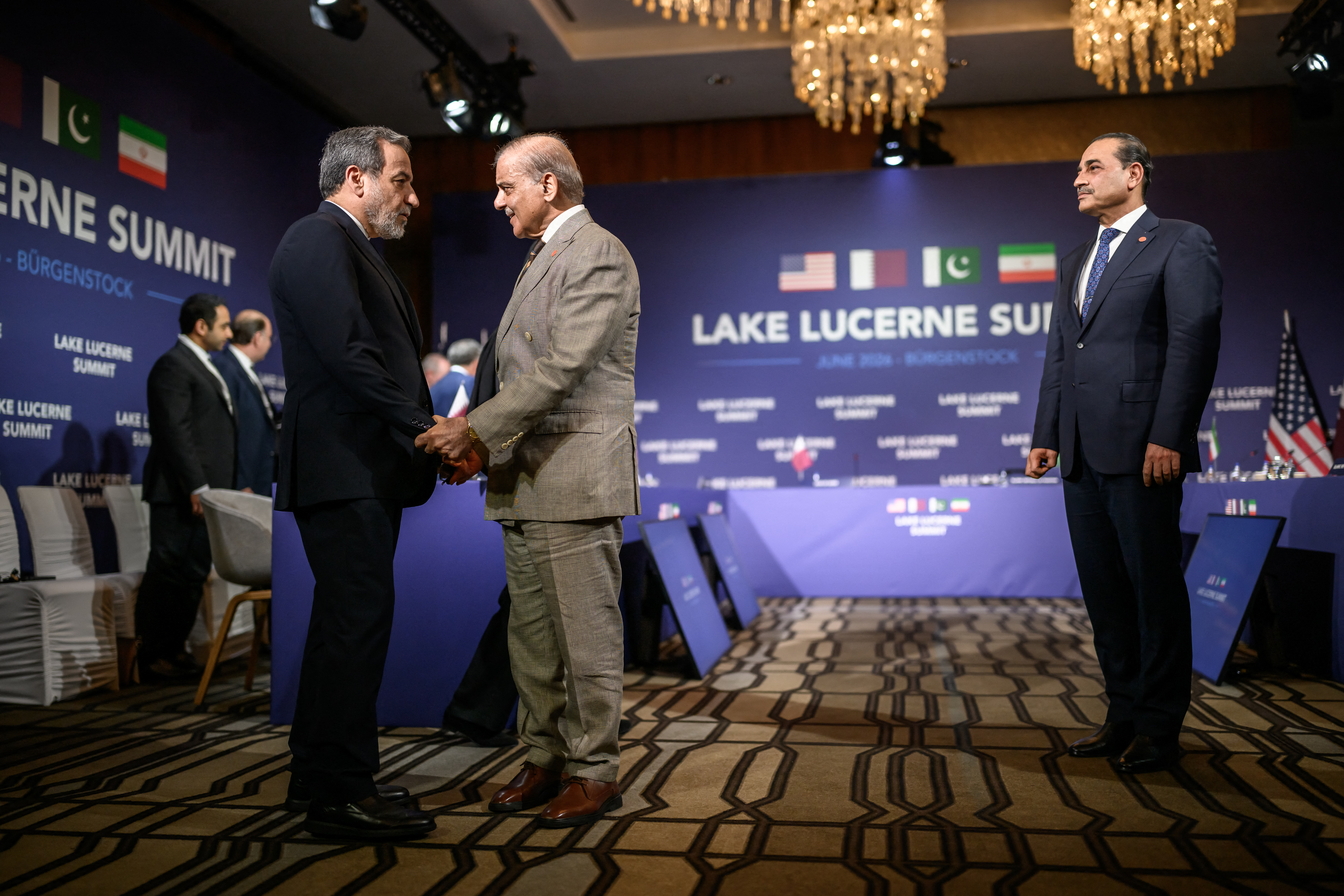 TOPSHOT - Iran's Foreign Minister Abbas Araghchi (L) shakes hands with Pakistan's Prime Minister Muhammad Shehbaz Sharif (C) next to Pakistan's Chief of Army Staff Field Marshal Asim Munir (R) prior to a quadrilateral meeting between the United States, Iran, Pakistan and Qatar at the Burgenstock luxury hotel complex overlooking Lake Lucerne, Switzerland, on June 21, 2026, as part of high-level talks aimed at advancing a deal to end the Middle East conflict.