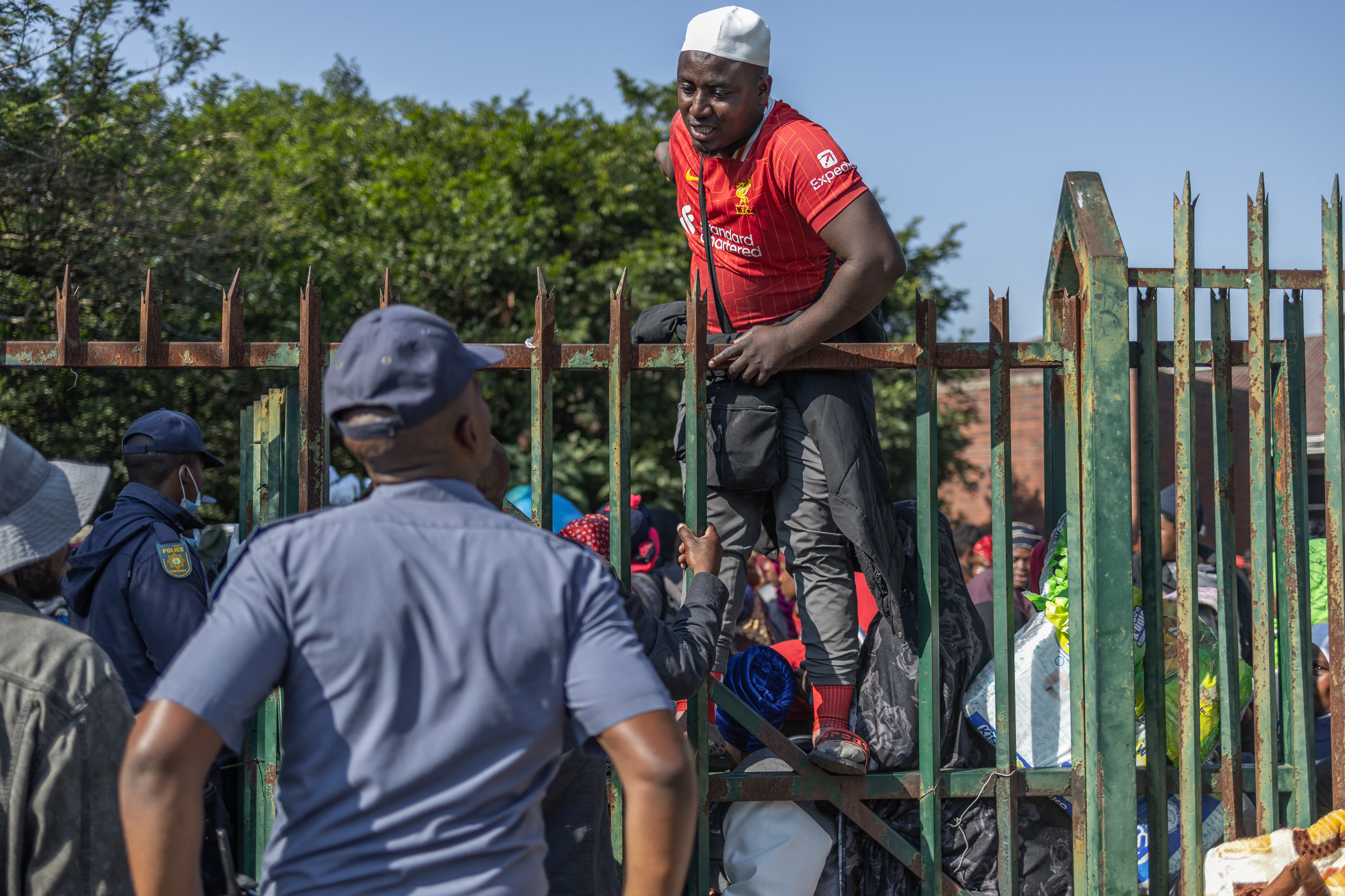 A displaced Malawian national speaks to a member of the South African Police Service (SAPS) while taking shelter at an abandoned municipality building on Mayor’s Walk in Pietermaritzburg on June 23, 2026 after fleeing their homes amid fears of xenophobic attacks and threats from anti-illegal immigration groups.
