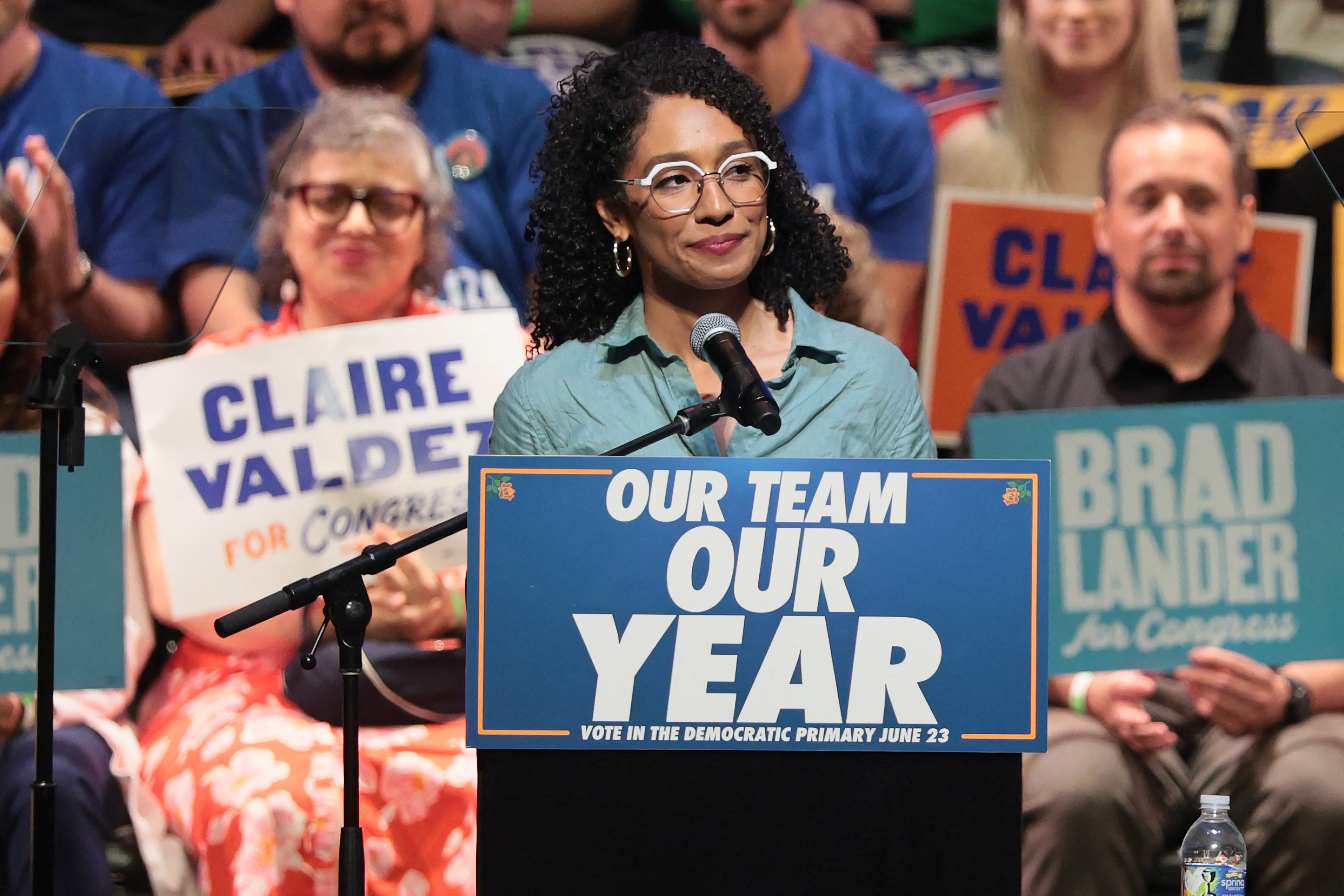 Darializa Avila Chevalier speaks at a podium during a campaign rally, with supporters behind her