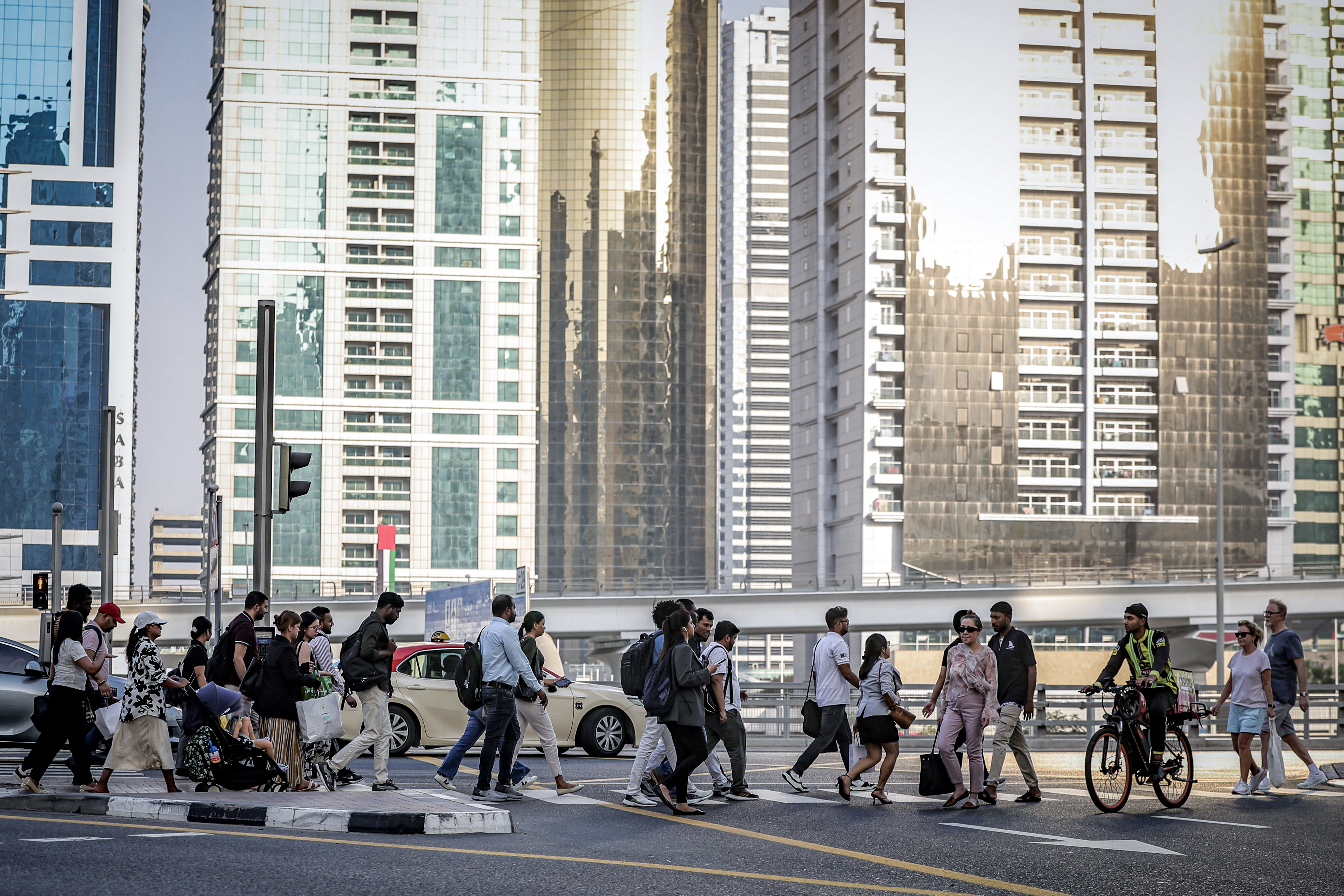 People cross a street while returning home from work, in Dubai on June 23, 2026.