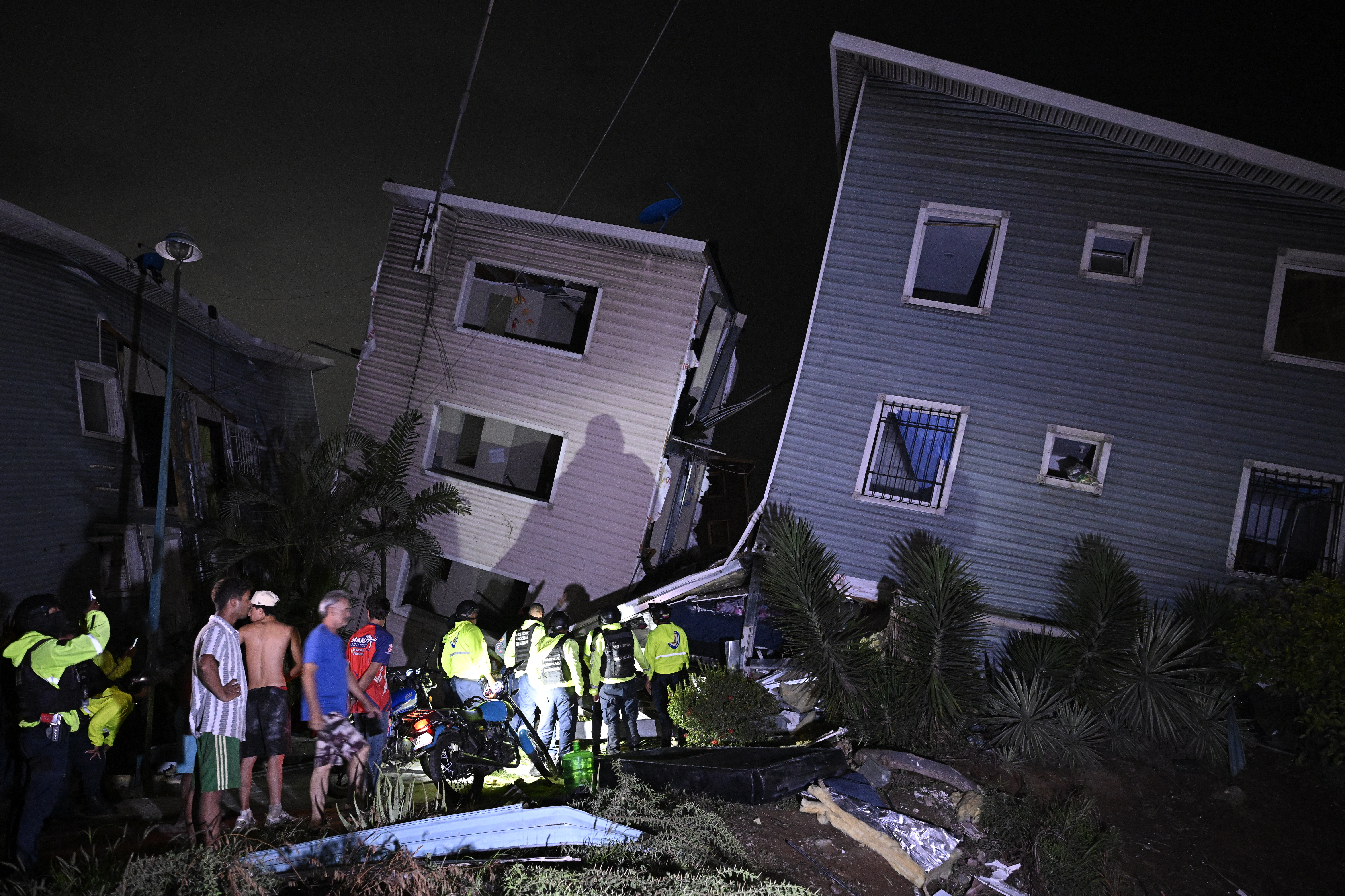 Residents and emergency workers stand near damaged buildings following an earthquake in Catia La Mar, some 30kms north-west of Caracas, early on June 25, 2026.