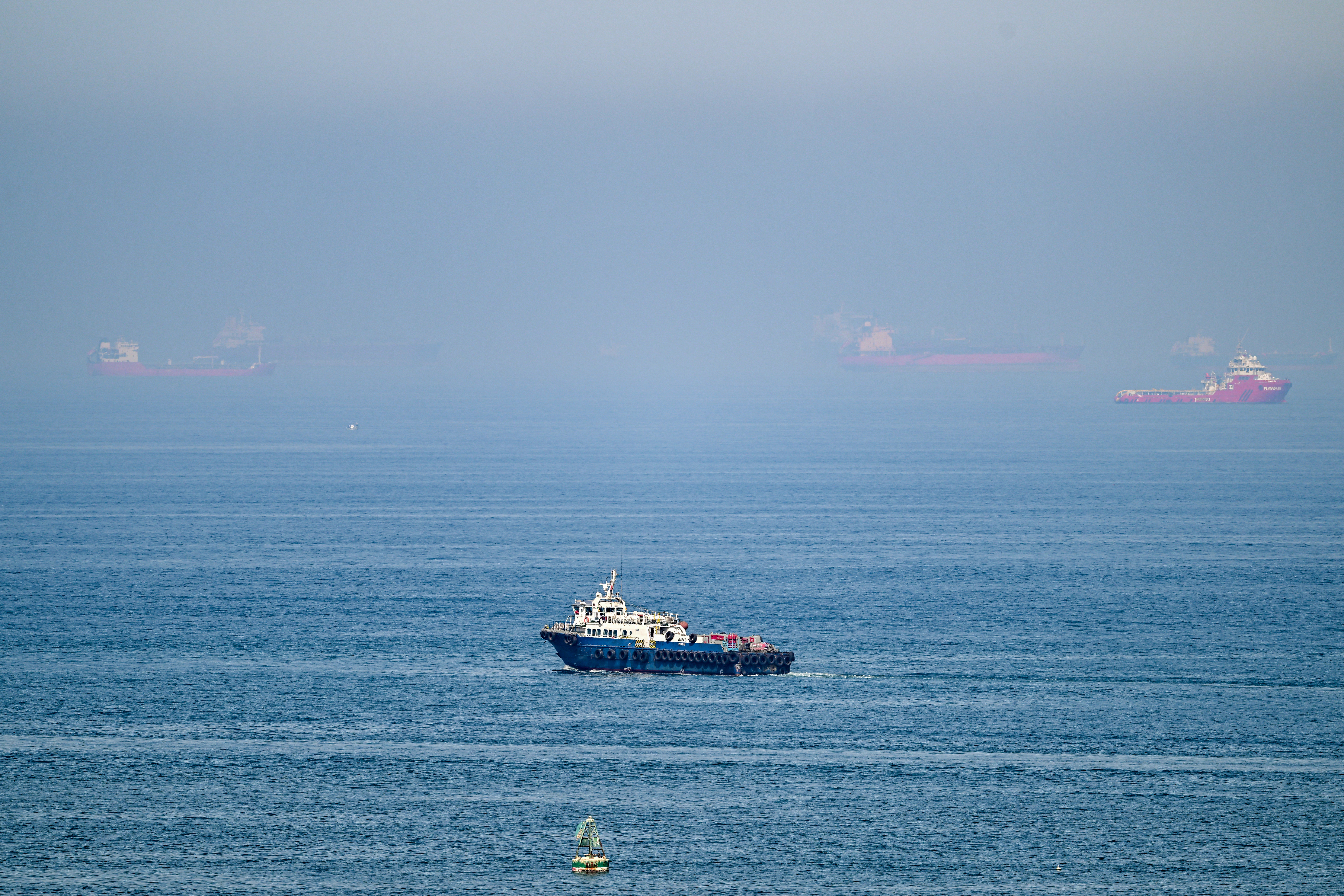 Cargo ships are pictured off cost of the Khor Fakkan Container Terminal, the only natural deep-sea port in the region and one of the major container ports in Sharjah Emirate, along the Gulf of Oman on June 19, 2026.