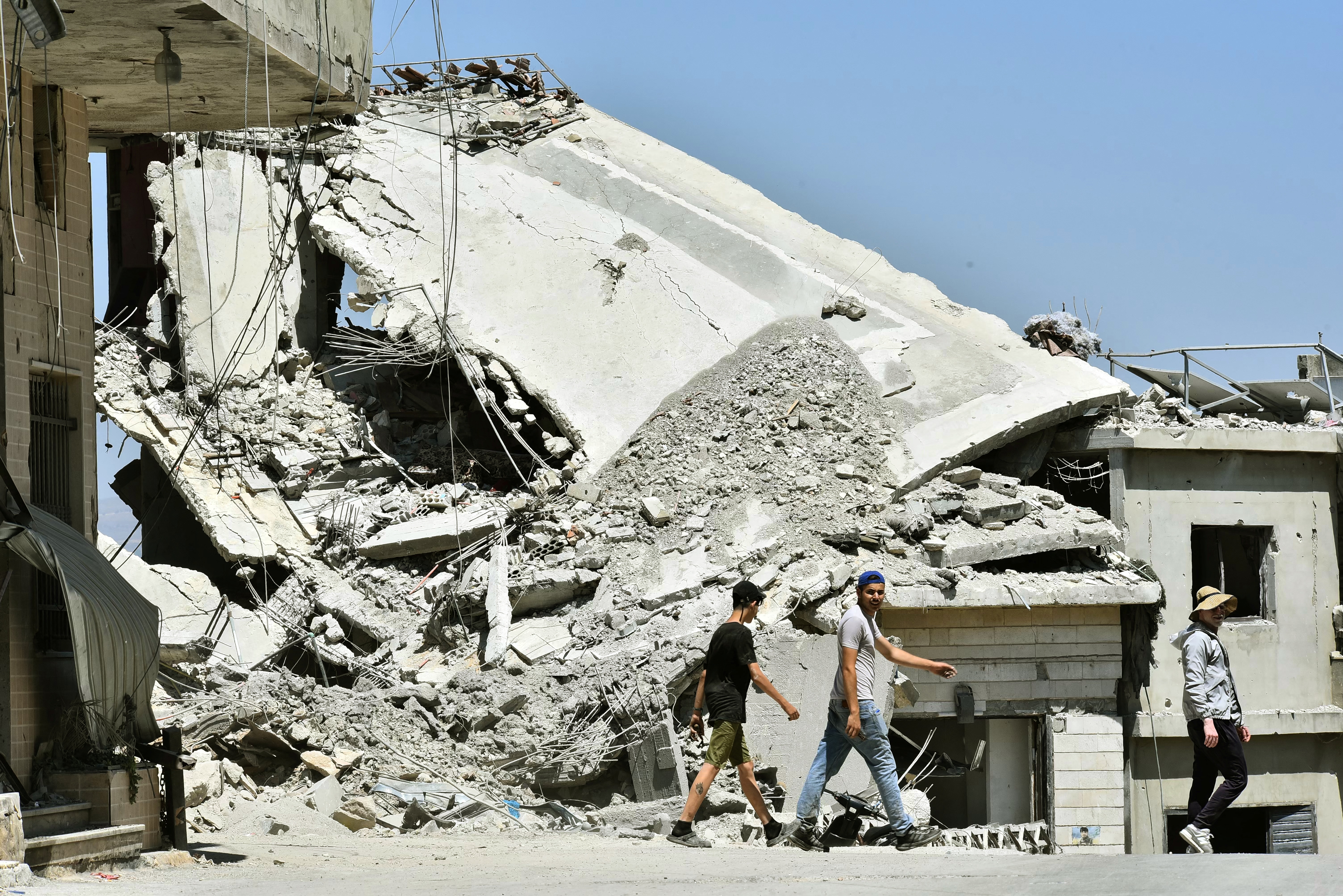 Residents walk past the rubble of homes and businesses, destroyed in Israeli military strikes, in the southern Lebanese village of Srifa on June 24, 2026.