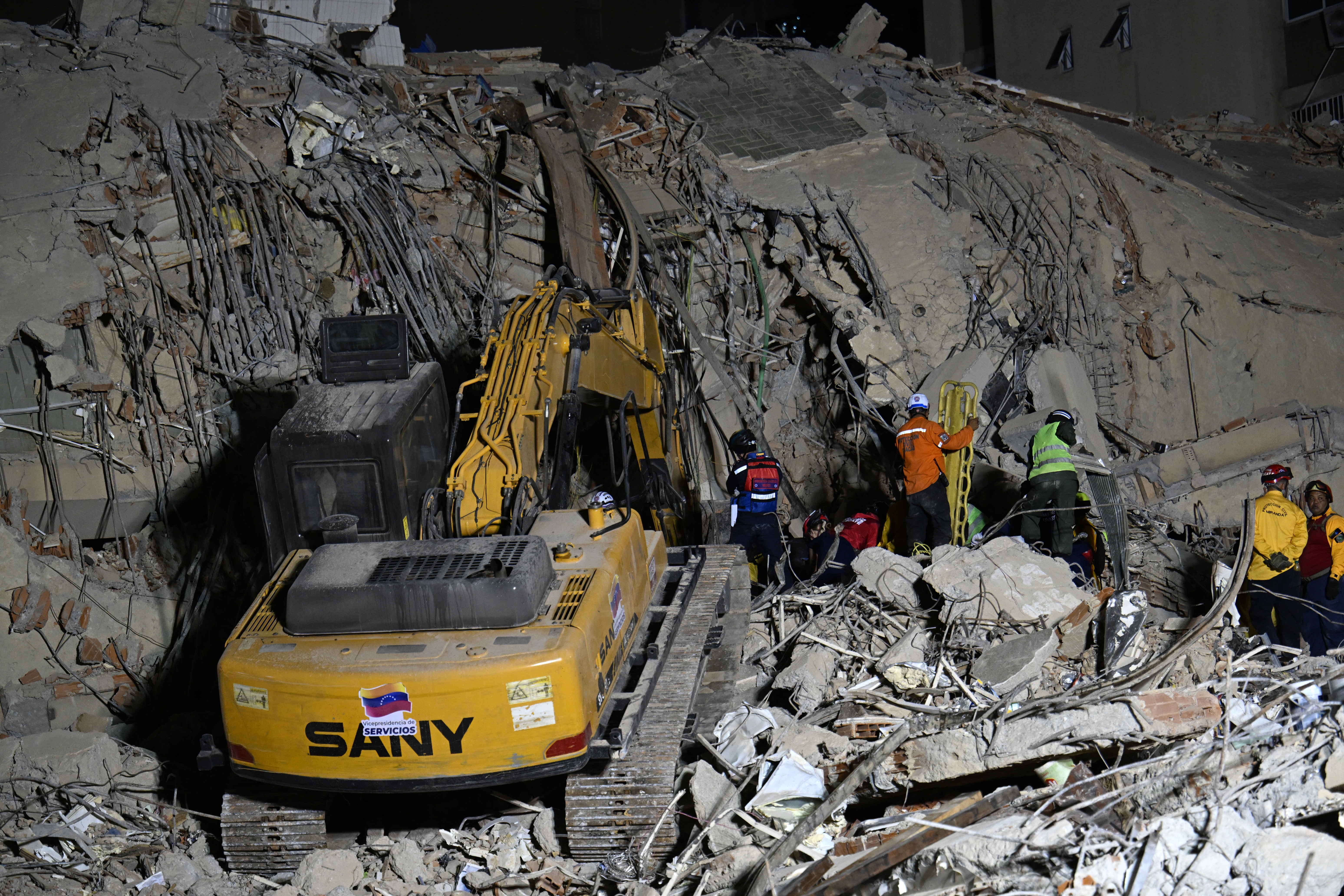 Rescue teams operate heavy machinery at the site of a collapsed building in Caracas on June 25, 2026, following earthquakes.