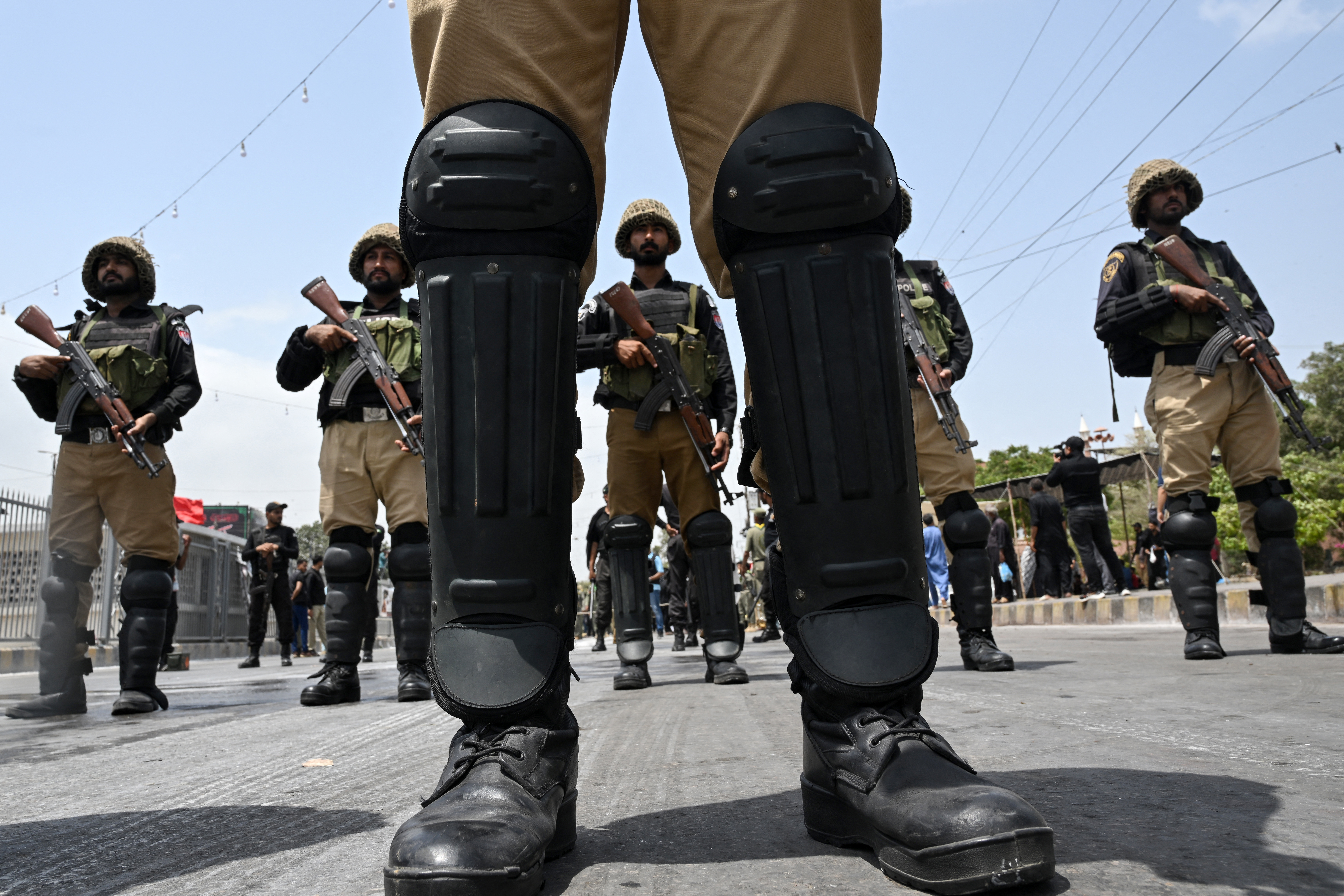 Security personnel stand guard along a road during a religious procession on the eighth day marking the Islamic holy month of Muharram in Karachi on June 24, 2026.