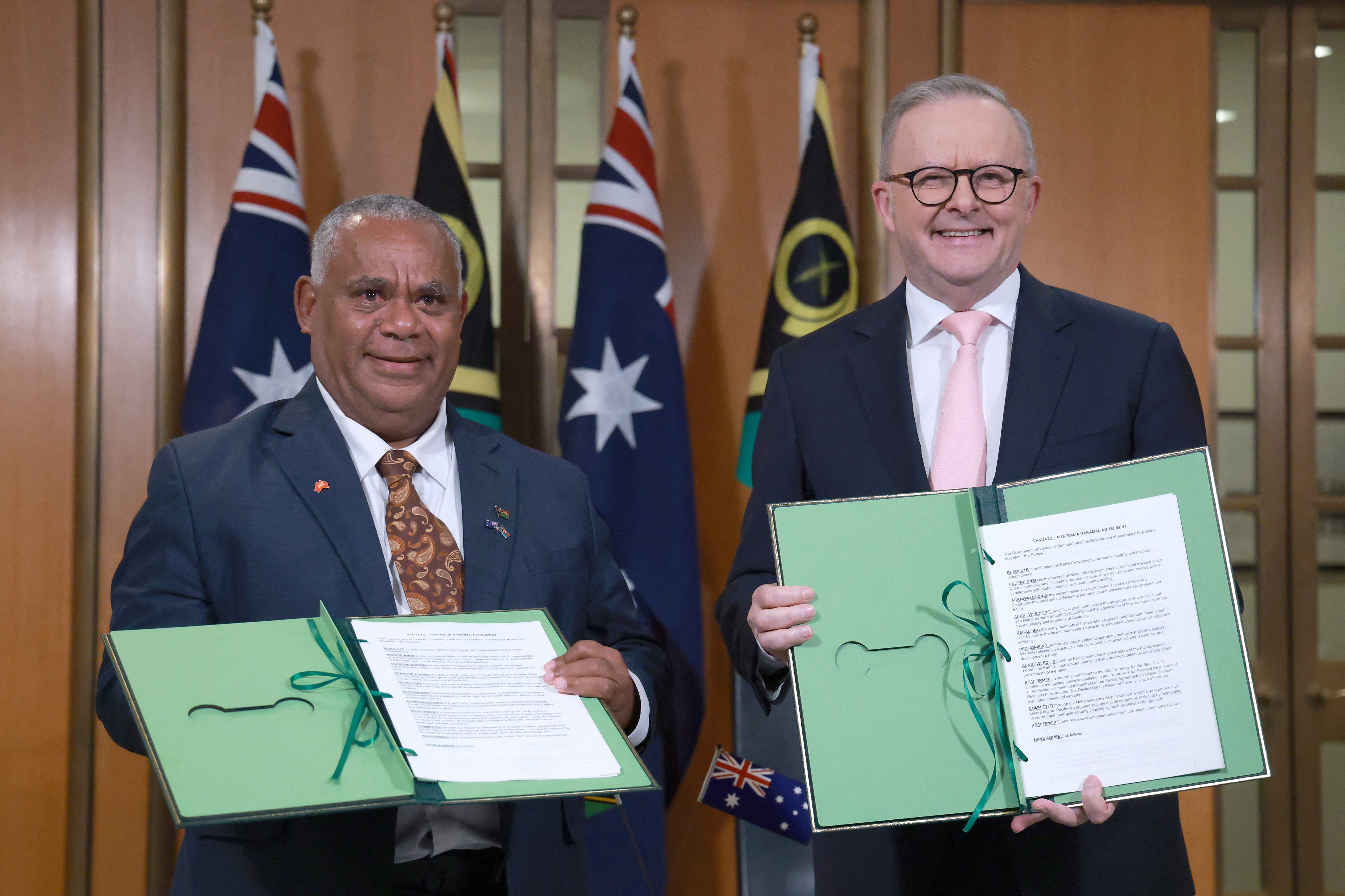 Australian Prime Minister Anthony Albanese (R) and Vanuatu's Prime Minister Jotham Napat pose with signed documents.
