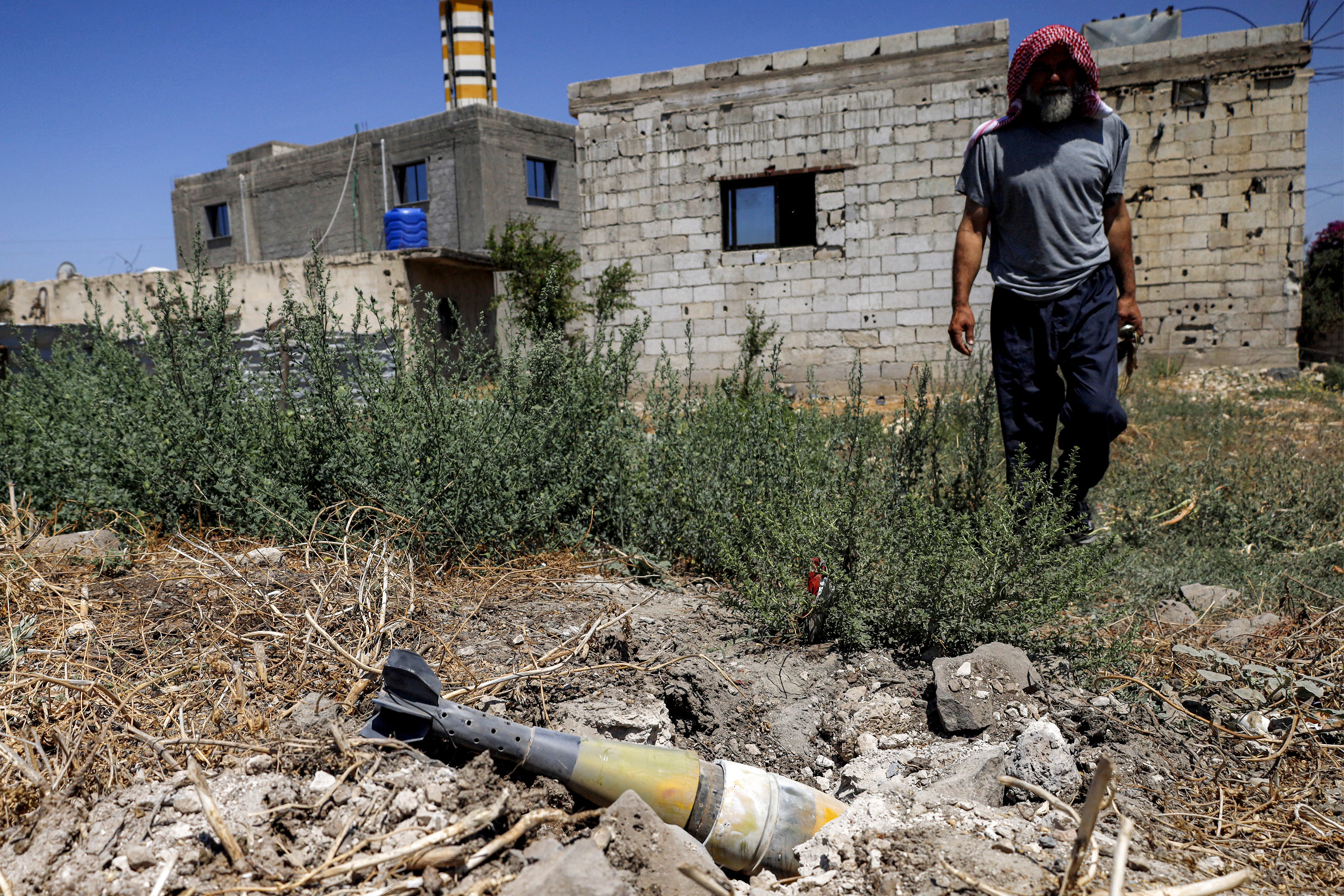 A man stands near an unexploded artillery shell that fell during reported overnight Israeli bombardment that hit the village of Abidin in Syria's southwestern Daraa province, close to the Golan Heights, on June 29, 2026.