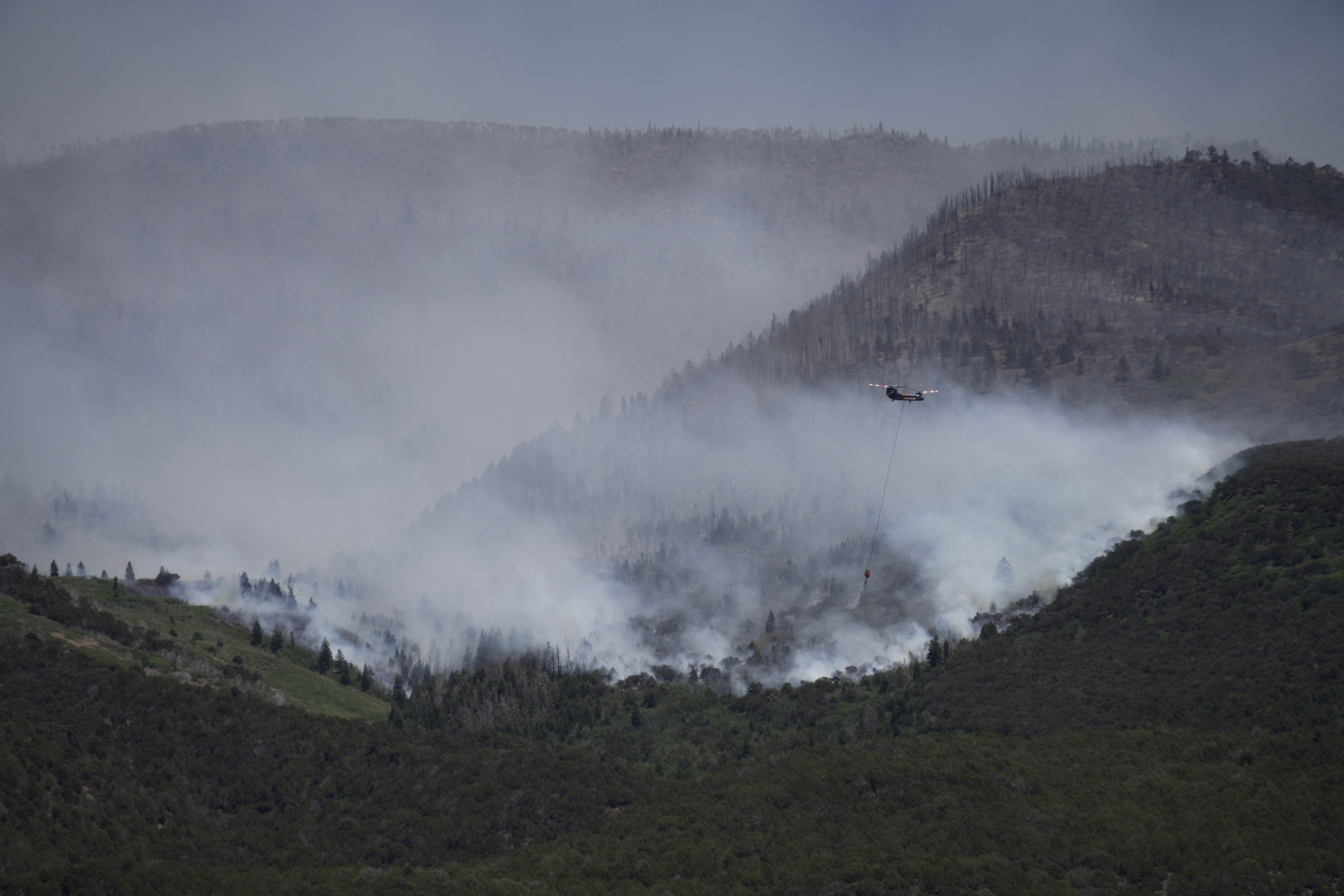 A helicopter drops water on the Cottonwood Fire in Beaver, Utah, on Saturday, June 27, 2026. (AP Photo/Ty ONeil)