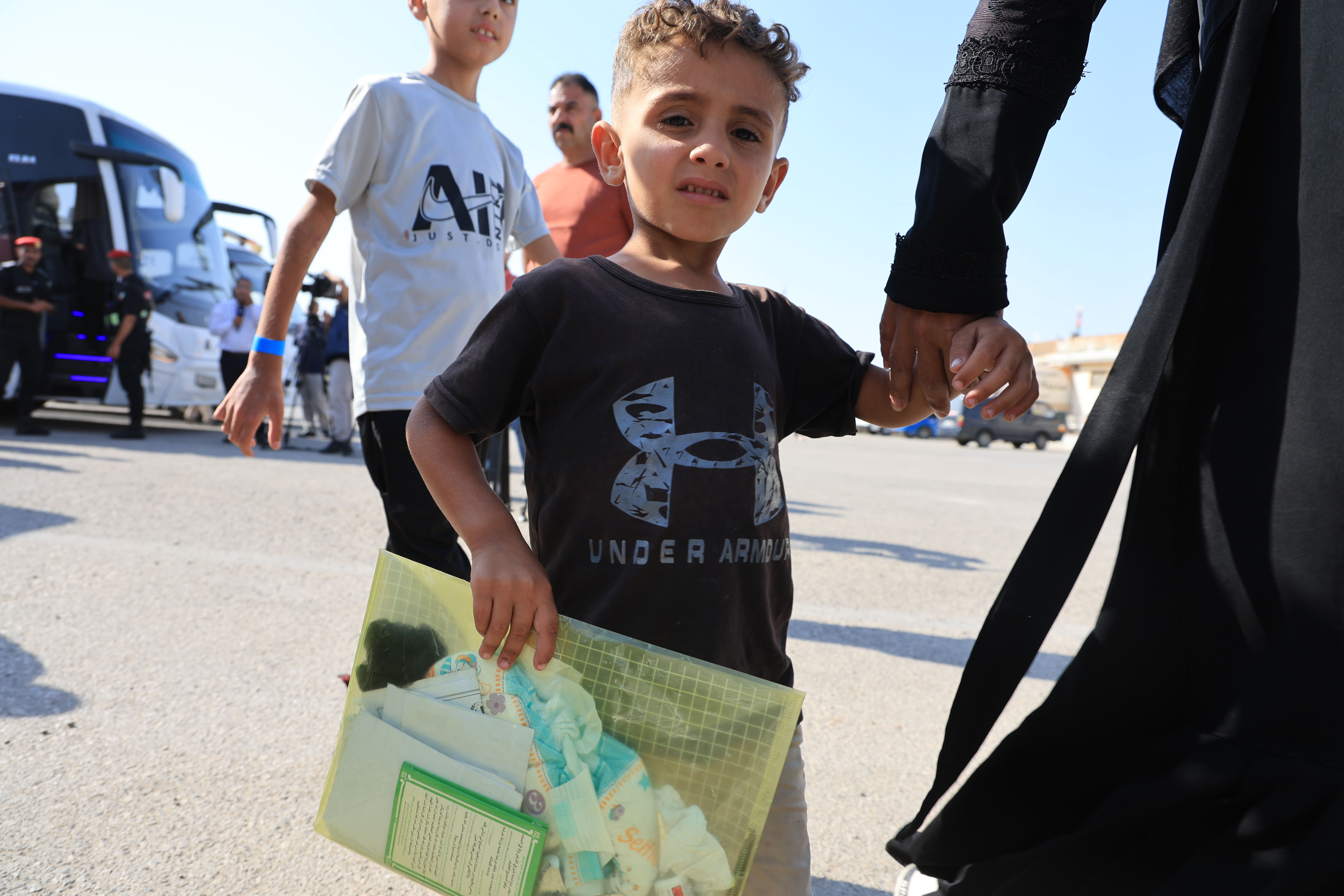 SOUTH SHUNA, JORDAN - JUNE 11: A child holds his medical reports alongside his mother as they join other pediatric patients who have been evacuated from Gaza arrive at the border with Israel on June 11, 2025 in South Shuna, Jordan. 16 child patients, 10 of whom are being treated for cancer, and 48 family companions arrived on Wednesday, the fifth such medical evacuation of sick children from Gaza for treatment in Jordan, more than 2.5 years into the war between Israel and Hamas. (Photo by Salah Malkawi/Getty Images)