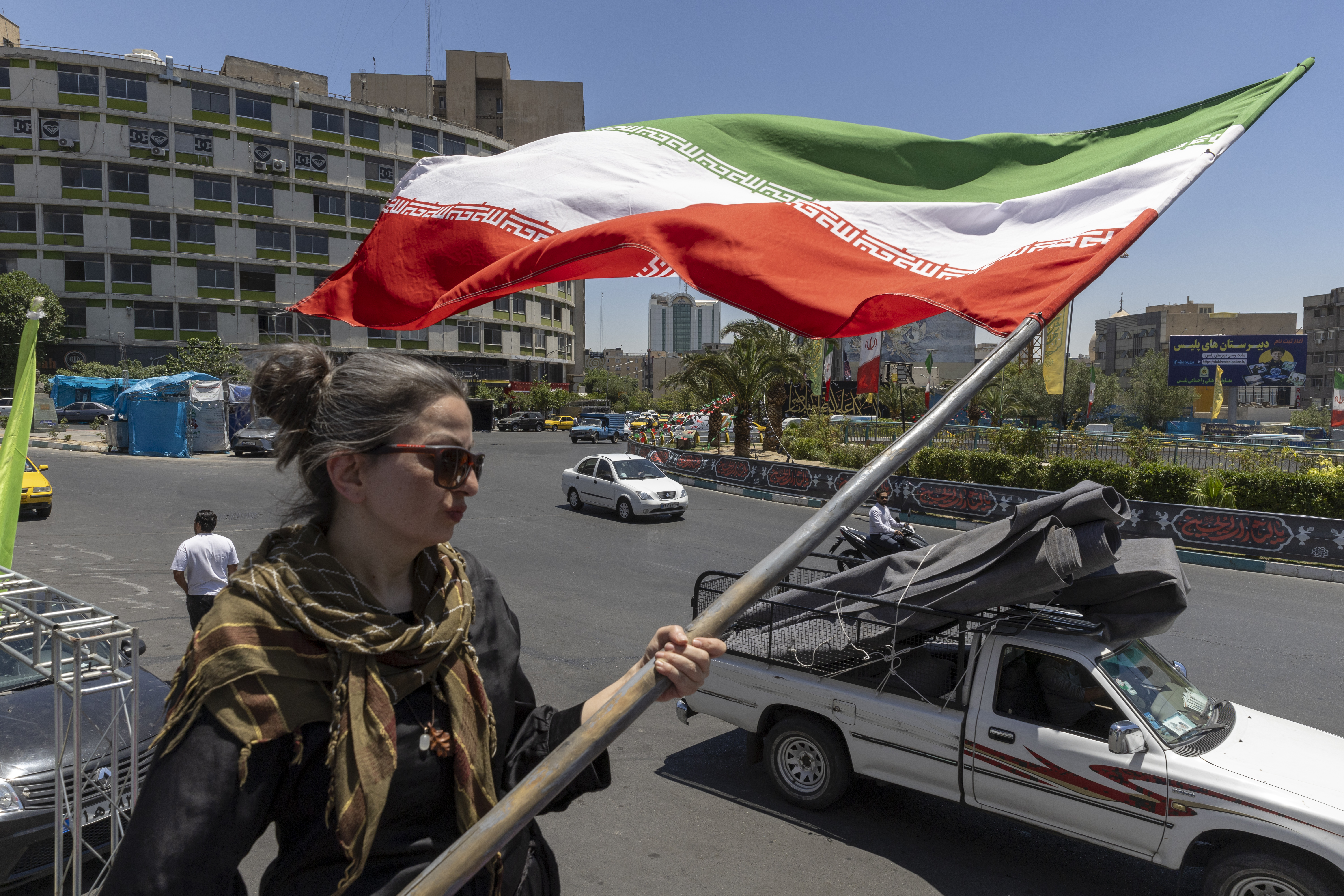 TEHRAN, IRAN - JUNE 15: A woman waves an Iranian flag on June 15, 2026 in Tehran, Iran. According to reports, the U.S. and Iran have signed a preliminary agreement to end the war and open the Strait of Hormuz. (Photo by Majid Saeedi/Getty Images)