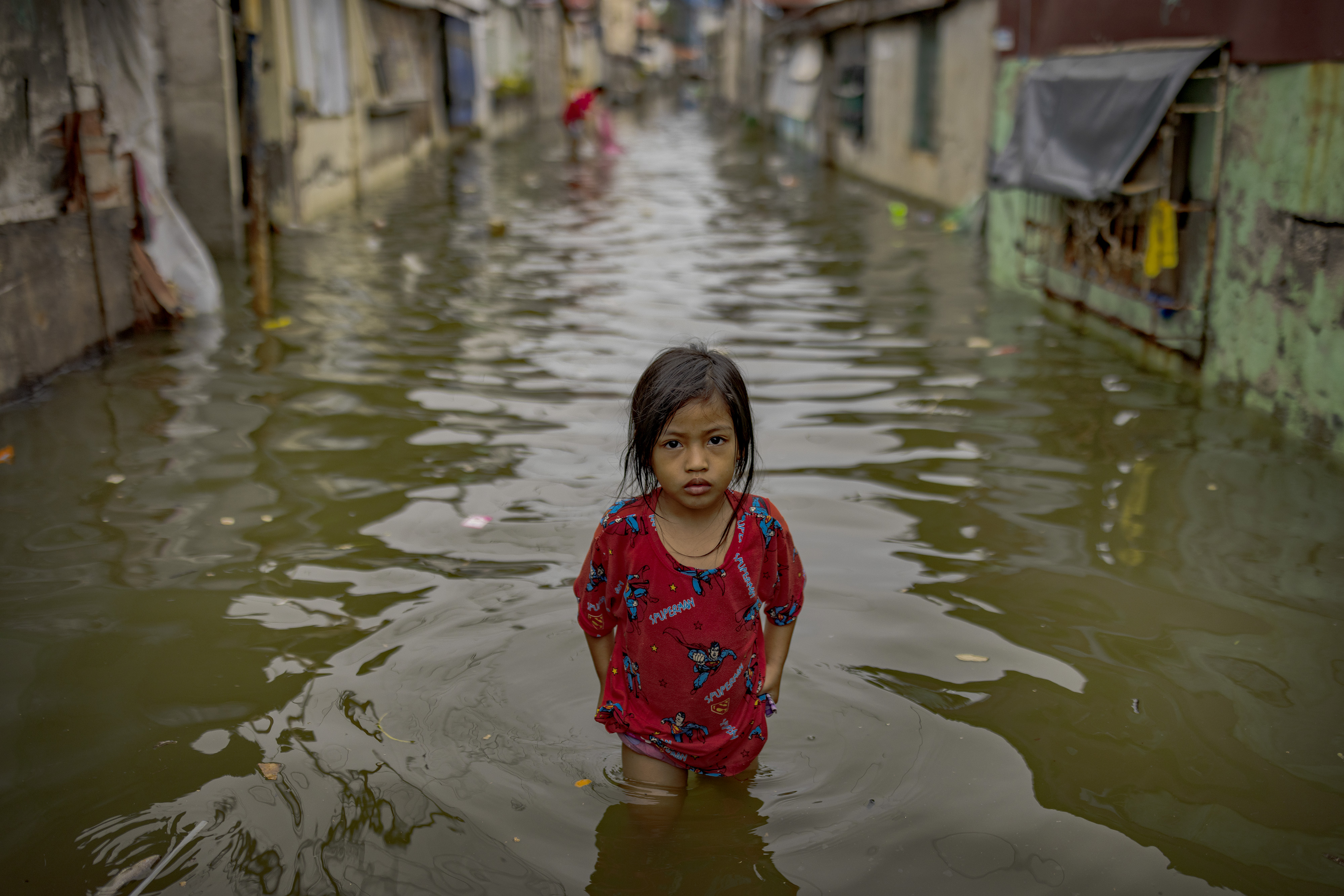 A girl wades a street flooded with seawater amid rising tides in Tibaguin Island, Hagonoy, Philippines