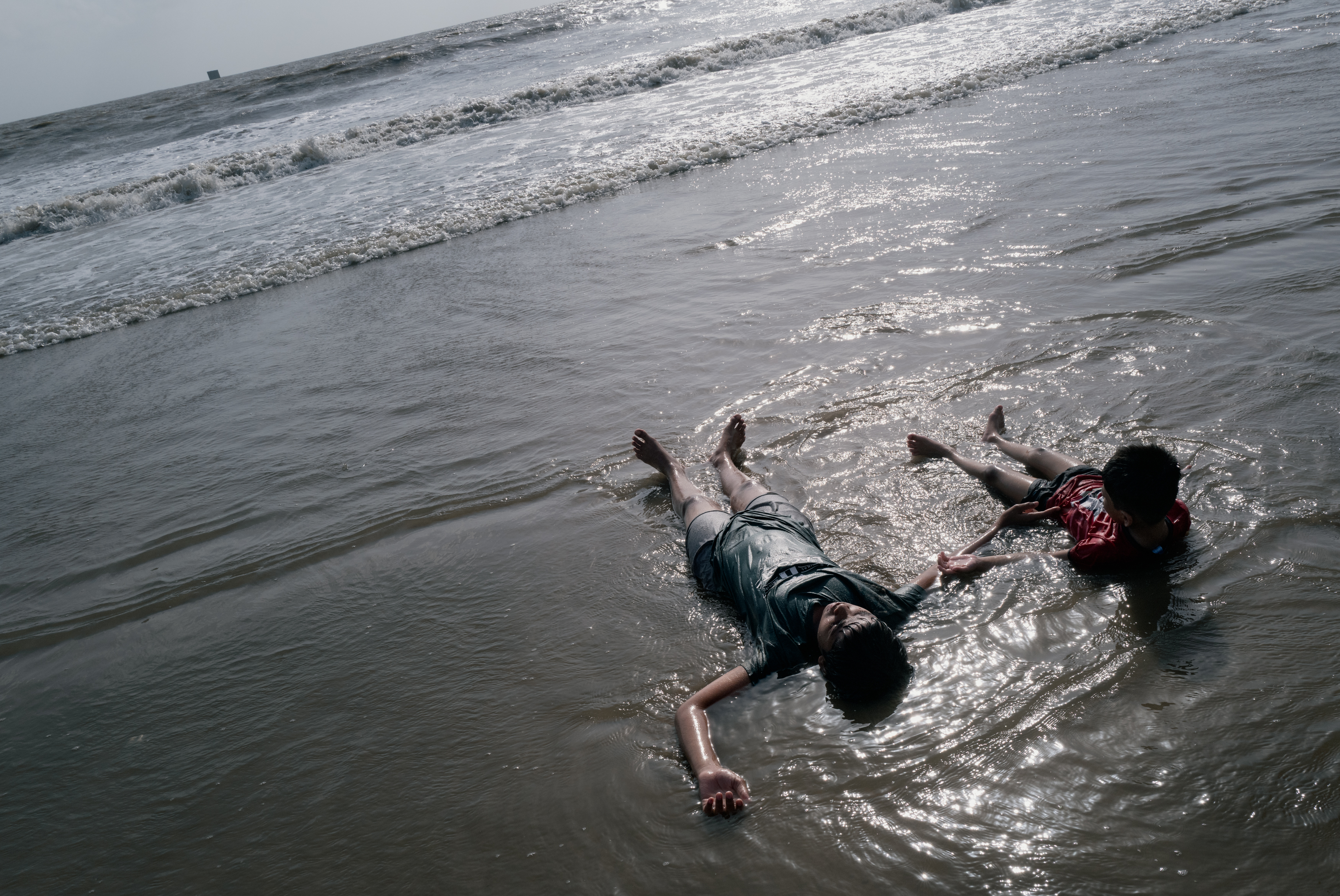 MUMBAI, INDIA - JUNE 13: Children cool off in the Arabian Sea on June 13, 2026 in Mumbai, India. Juhu Beach faces a severe plastic waste crisis. Millions of visitors, combined with the widespread use of single-use plastics, generate large amounts of litter along the shoreline. During the monsoon season, ocean currents wash ashore vast quantities of marine debris, with up to 1.5 lakh kilograms (150,000 kg) of waste accumulating on the beach each day. (Photo by Elke Scholiers/Getty Images)