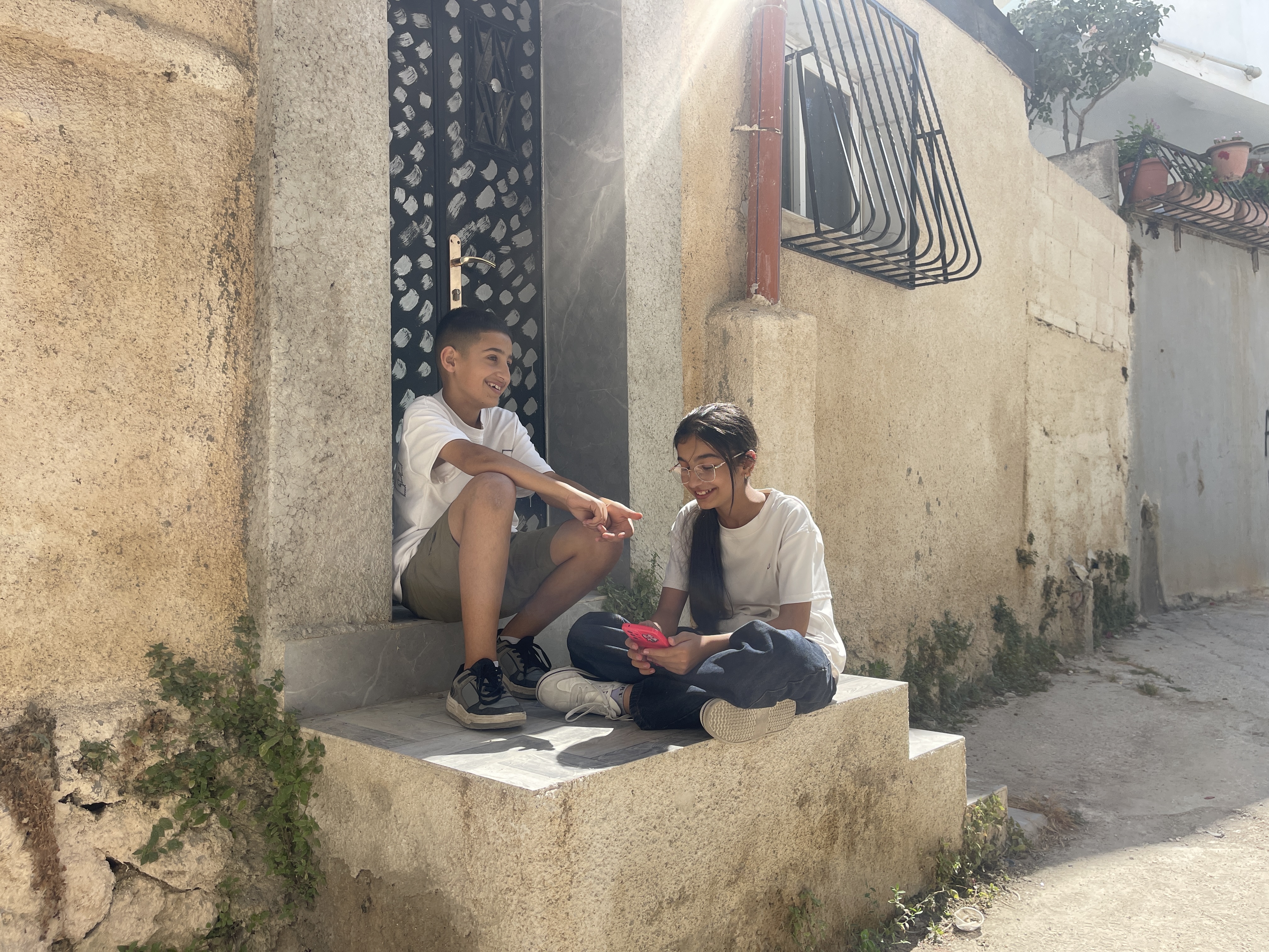 Mustafa Abu Aliyah, 13, and his sister Diyar, 12, sit in the alleyways of Dheisheh refugee camp in the occupied West Bank [Leila Warah/Al Jazeera].