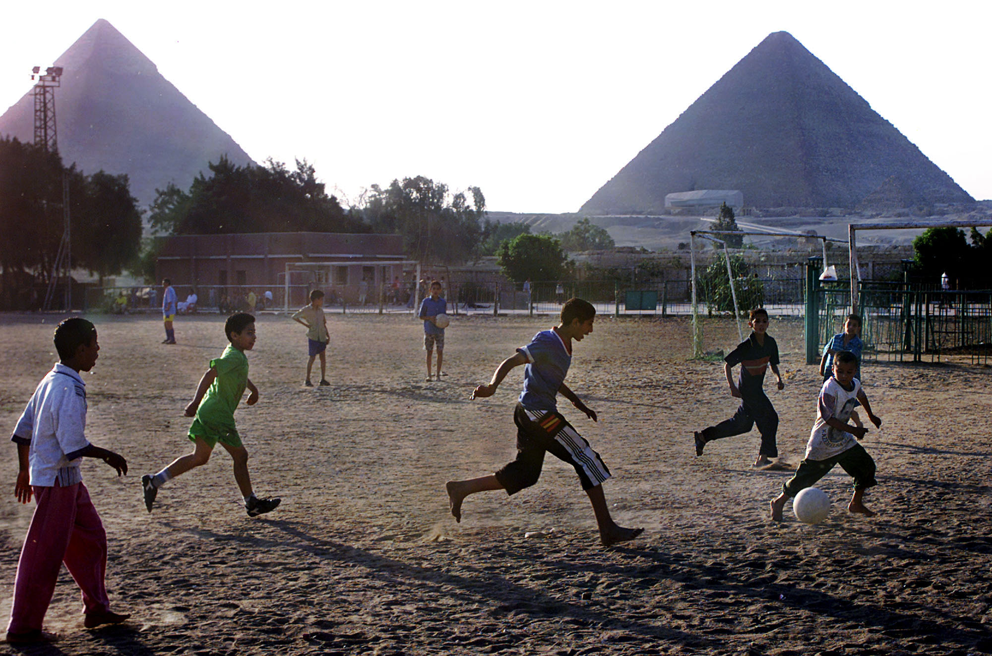 Egyptian children play soccer in front of the Giza Pyramids in Giza Friday, May 17, 2002 ahead of the World Cup soccer tournament which kicks off May 31 in Korea. Egypt has qualified twice for the World Cup in the last 60 years, 1934 and 1990. (AP Photo/Amr Nabil)