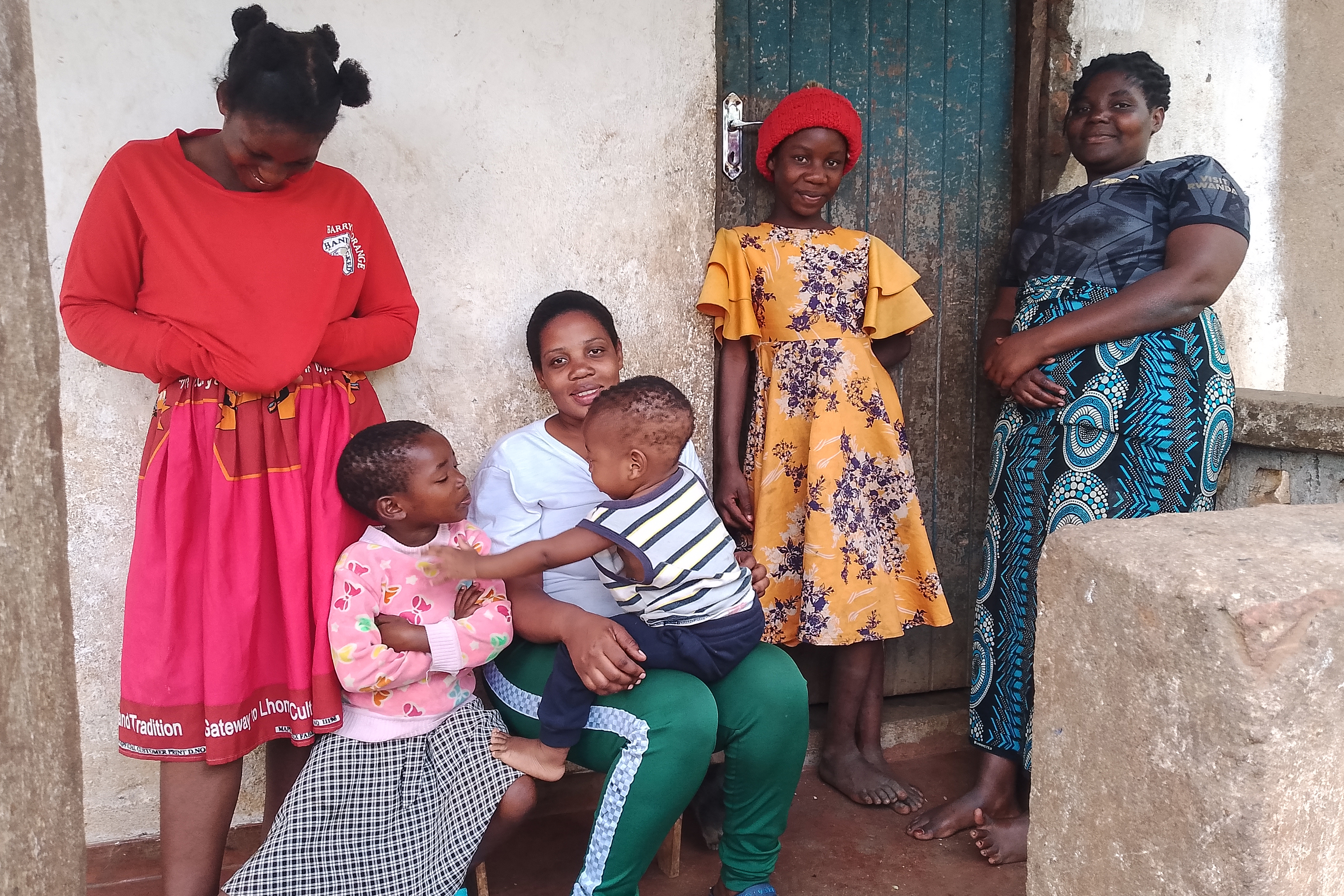Janet pose for a photo with youngest child and family members [Charles Pensulo/Al Jazeera]