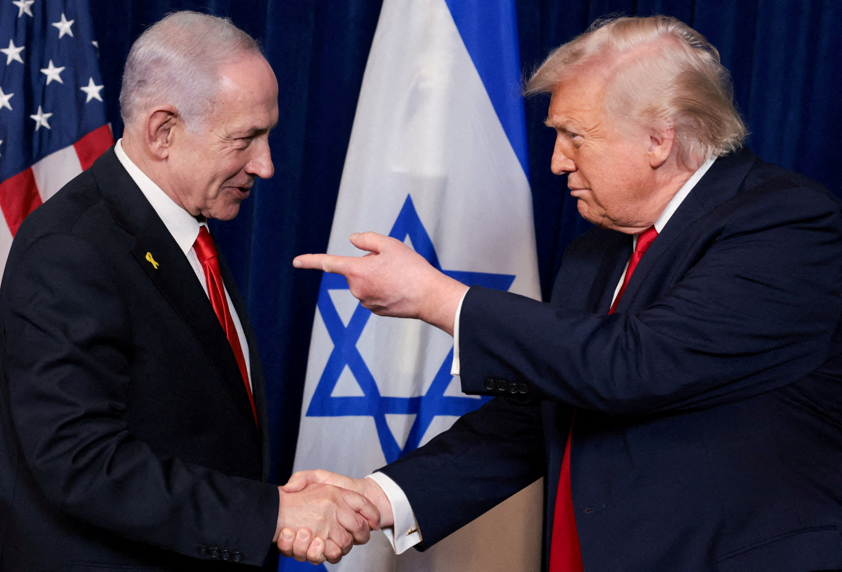 FILE PHOTO: U.S. President Donald Trump points his finger towards Israeli Prime Minister Benjamin Netanyahu as they shake hands during a press conference after meeting at Trump?s Mar-a-Lago club in Palm Beach, Florida, U.S., December 29, 2025. REUTERS/Jonathan Ernst/File Photo