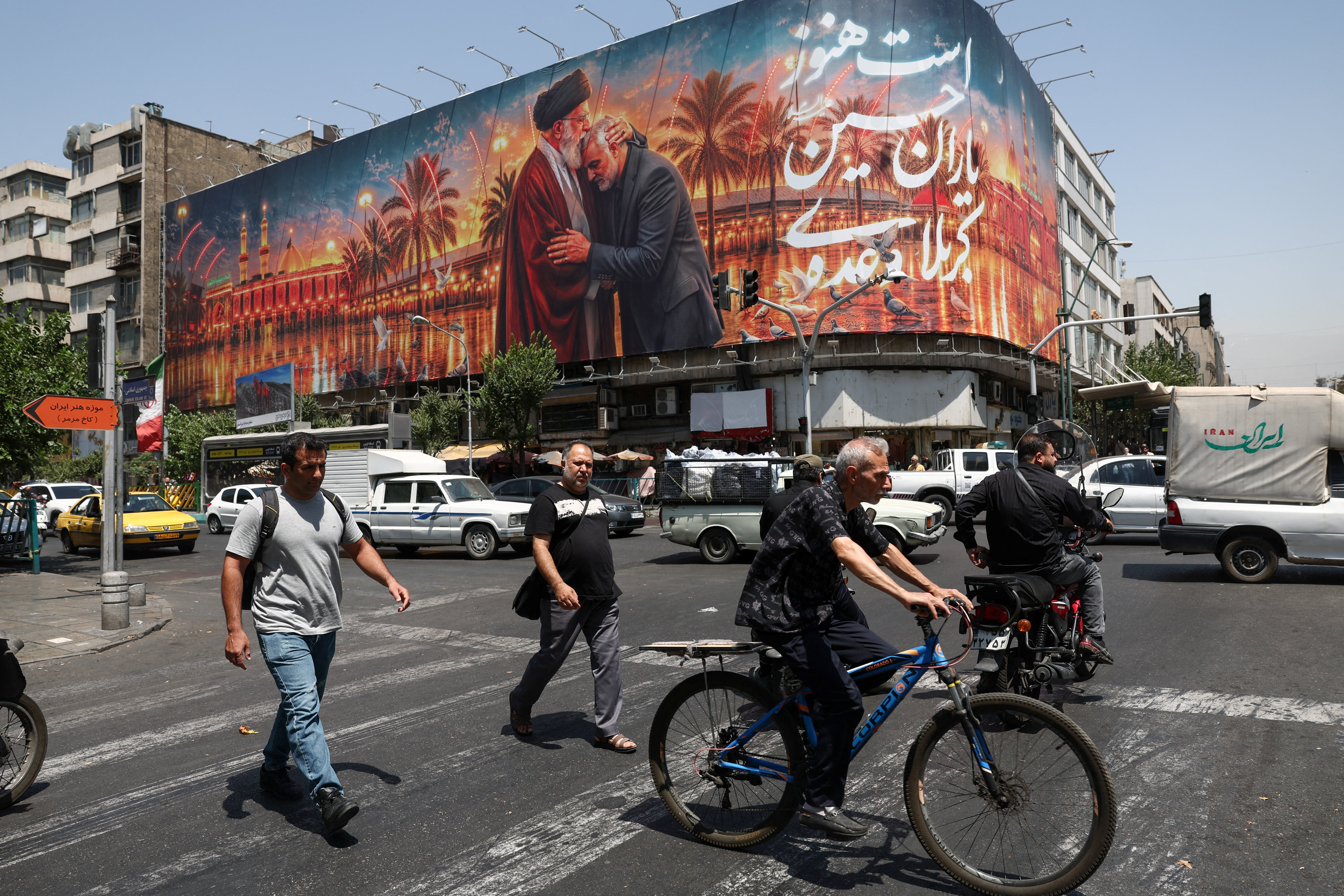 People move past a billboard with an image which depicts Iran's late Supreme Leader Ayatollah Ali Khamenei embracing late senior Iranian military commander General Qassem Soleimani, in Tehran, Iran, June 28, 2026. Majid Asgaripour/WANA (West Asia News Agency) via REUTERS ATTENTION EDITORS - THIS PICTURE WAS PROVIDED BY A THIRD PARTY. ISRAEL OUT. NO COMMERCIAL OR EDITORIAL SALES IN ISRAEL. NO ACCESS FOR ISRAELI MEDIA. NO USE BBC PERSIAN. NO USE VOA PERSIAN. NO USE MANOTO. NO USE IRAN INTERNATIONAL. NO USE RADIO FARDA. DIGITAL: NO USE BBC PERSIAN. NO USE VOA PERSIAN. NO USE MANOTO. NO USE IRAN INTERNATIONAL. NO USE RADIO FARDA.