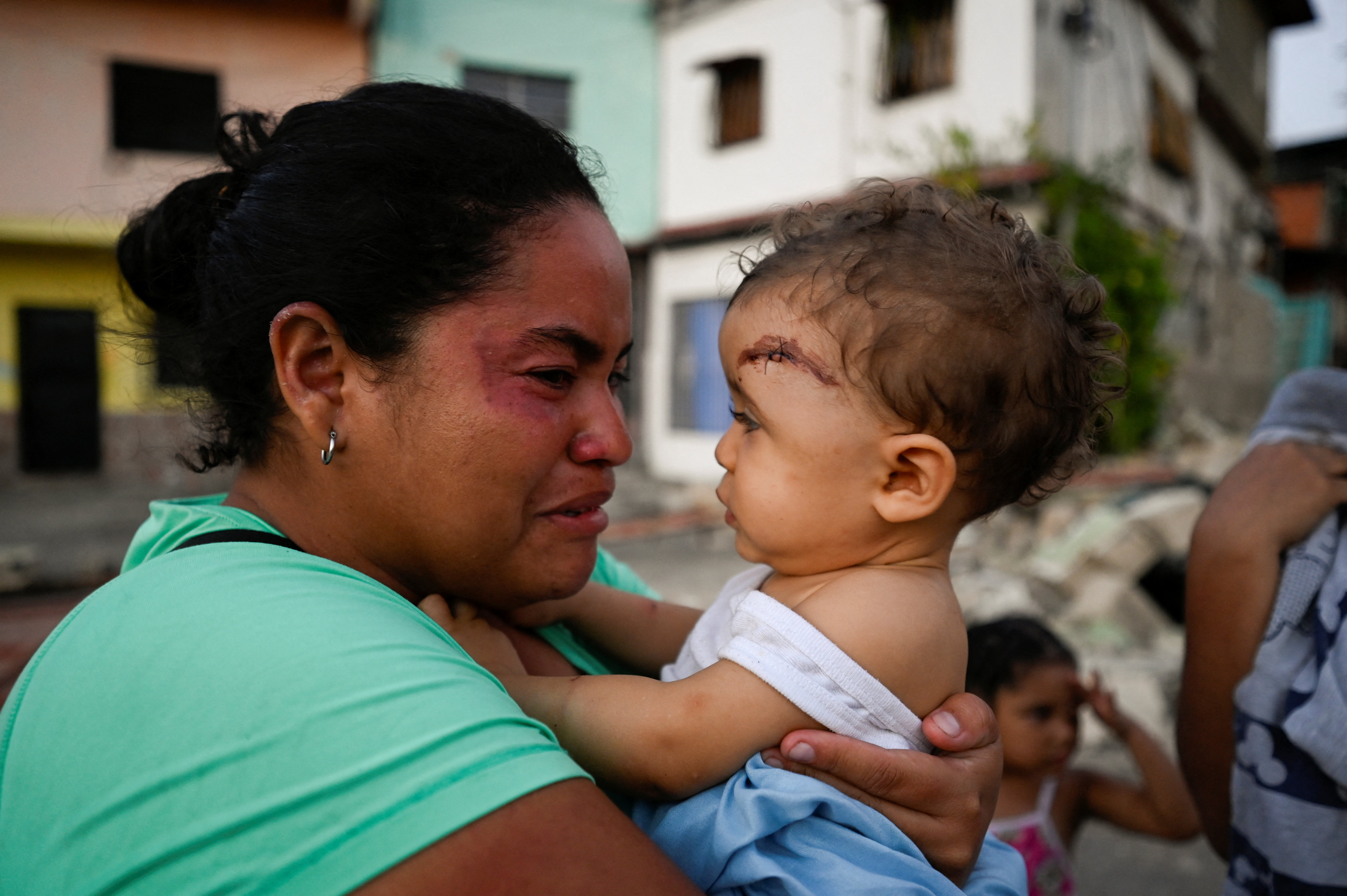 A woman reacts as she carries an injured child in the aftermath of earthquakes in La Guaira, Venezuela, June 25, 2026. REUTERS/Maxwell Briceno