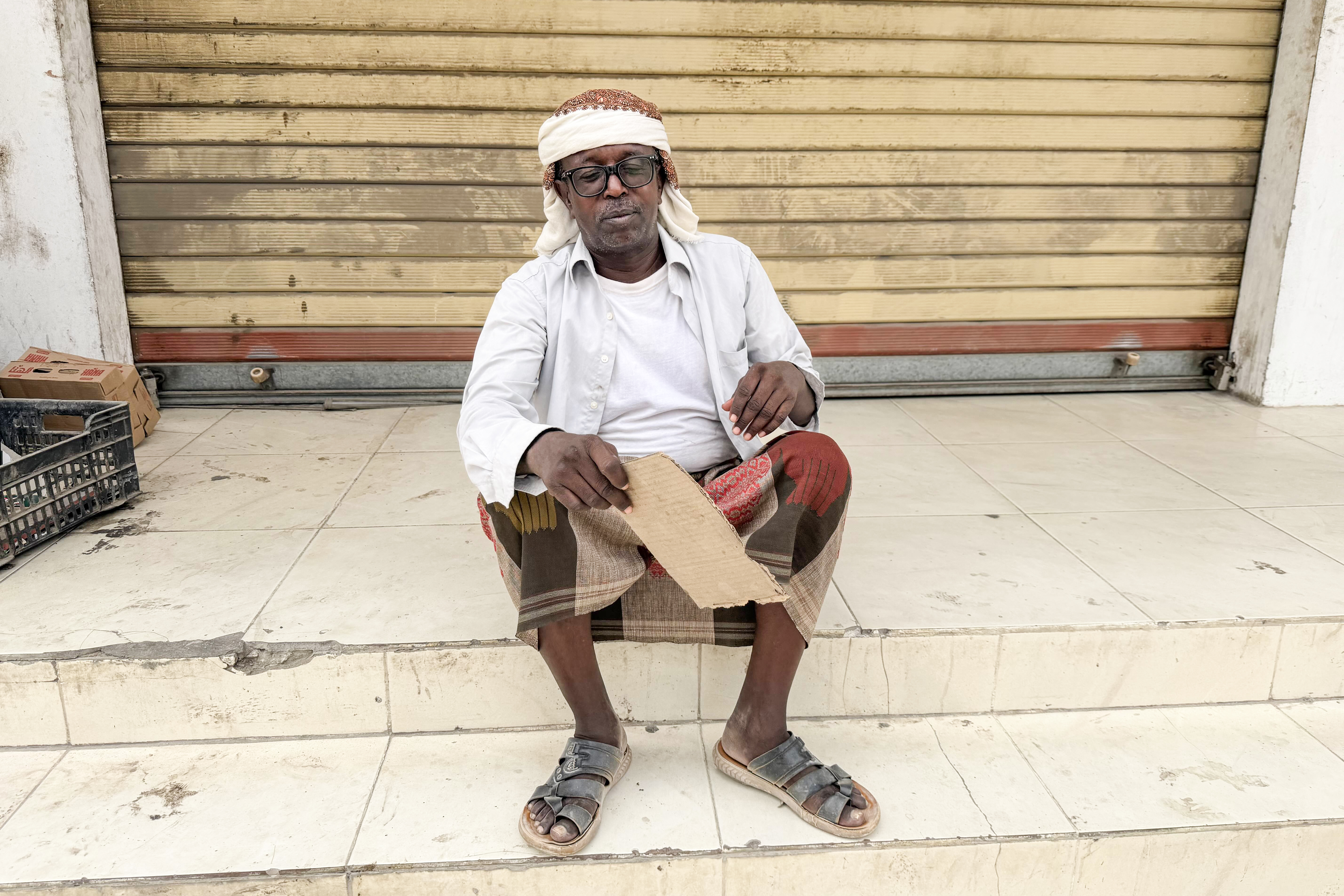 Salah Mohammed holds his shirt open and fans himself with a piece of cardboard during prolonged power cuts in Yemen's port city of Mukalla, where he and his wife often struggle to sleep amid scorching heat and high humidity.