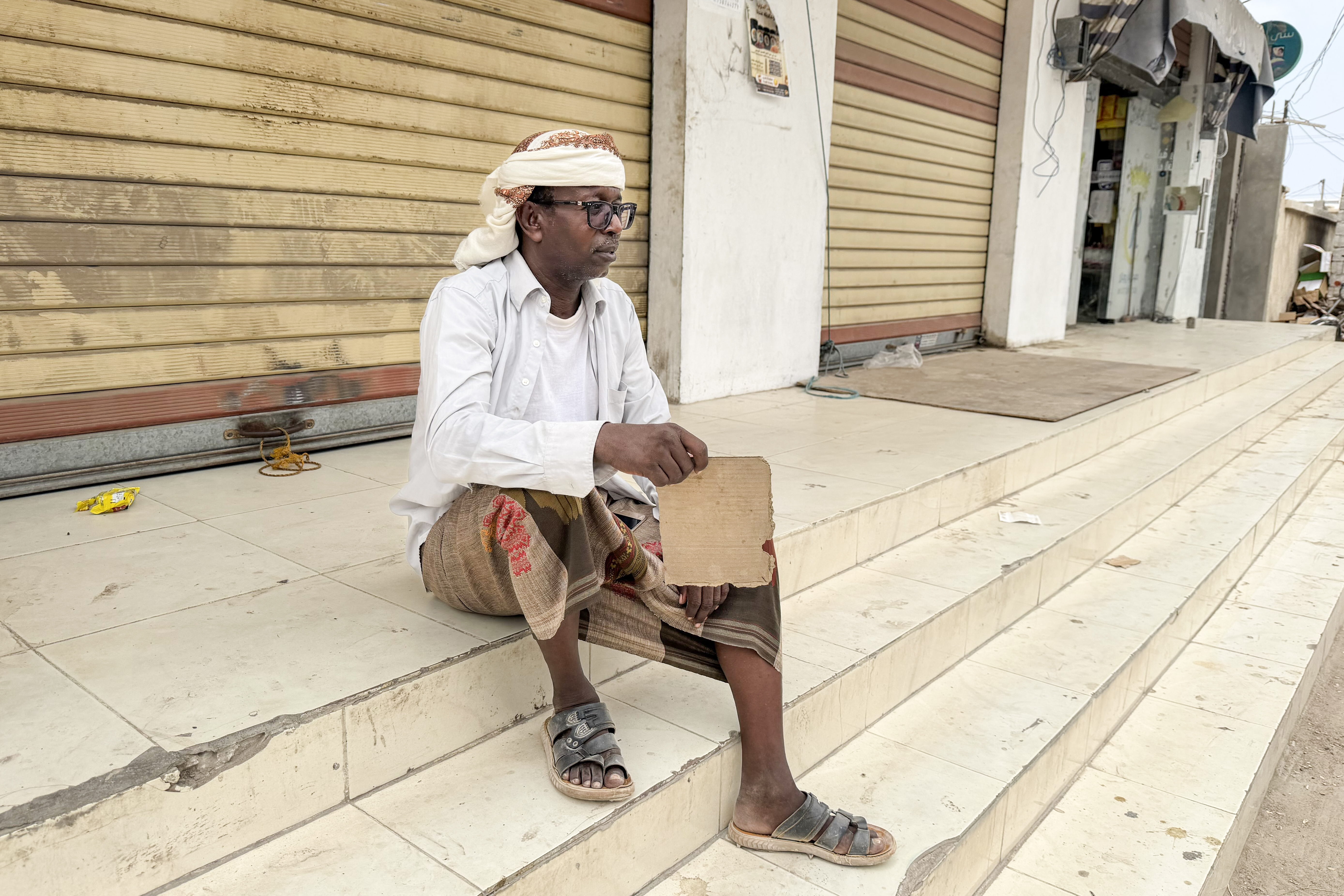 Salah Mohammed holds his shirt open and fans himself with a piece of cardboard during prolonged power cuts in Yemen's port city of Mukalla, where he and his wife often struggle to sleep amid scorching heat and high humidity. Saeed Al-Batati