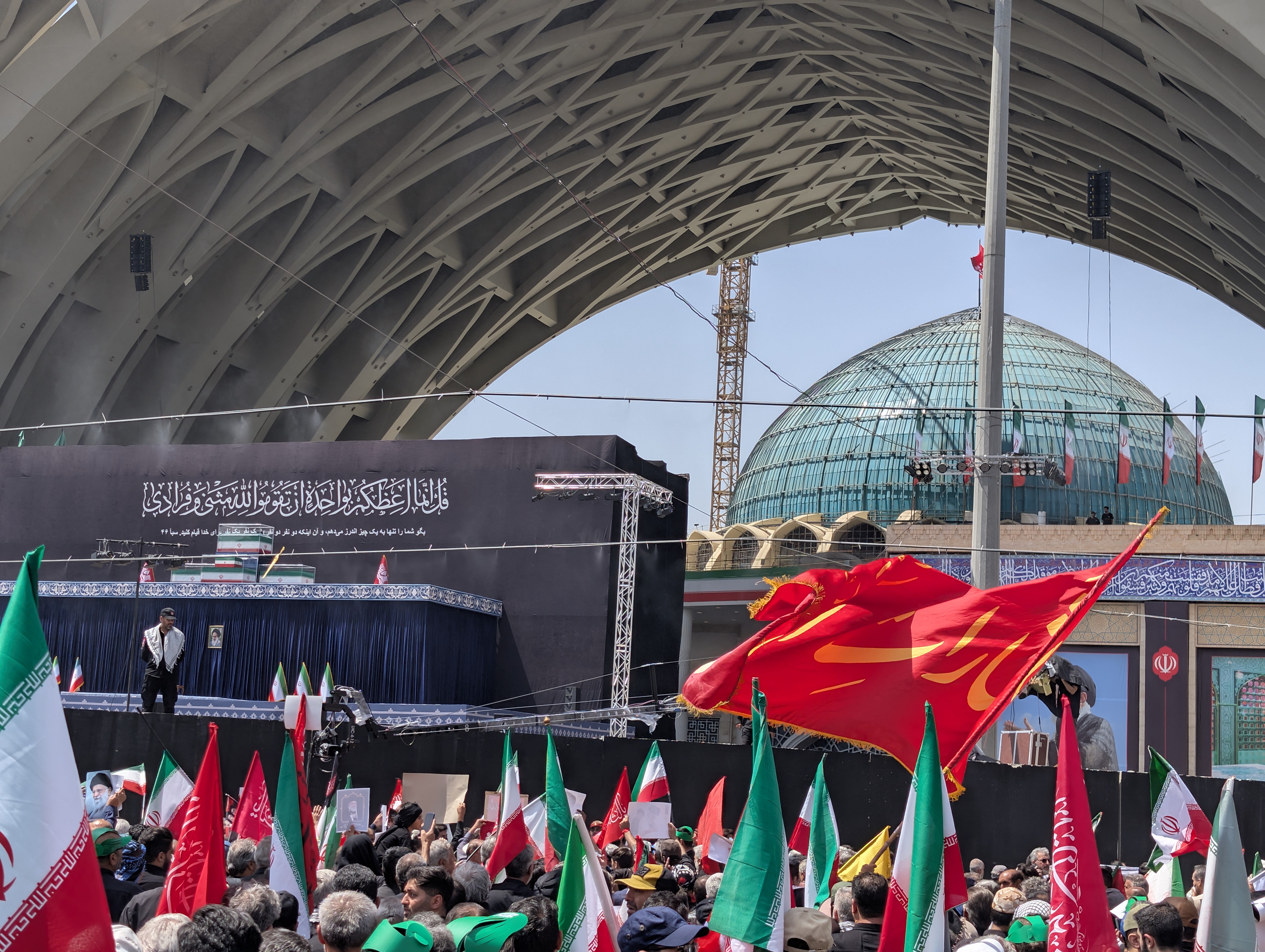 Red flags, associated with martyrdom in Shia Islam and carrying religious messages, were carried by mourners [Maziar Motamedi/Al Jazeera]
