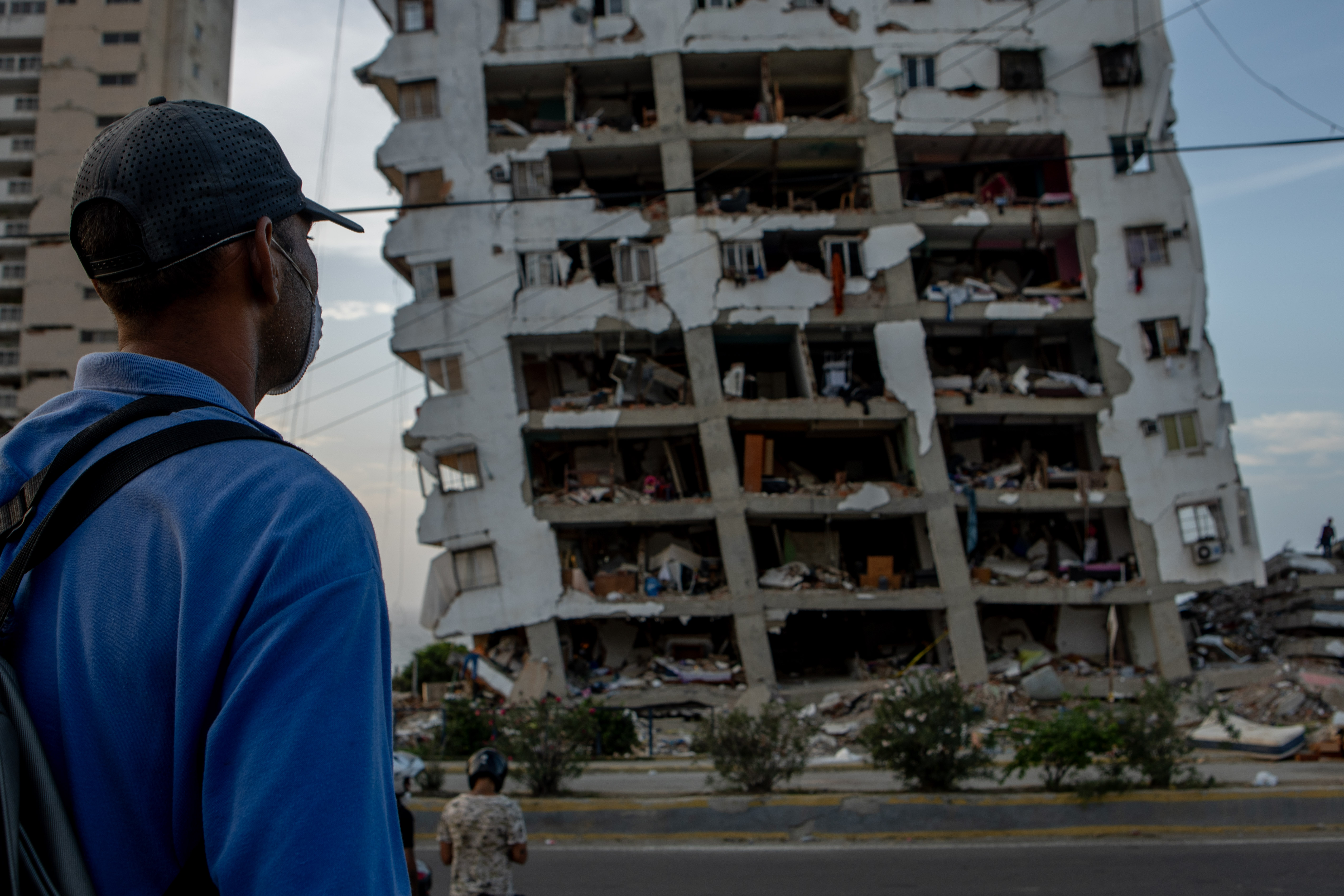 A man watches search efforts for his sister whose ground floor apartment was reduced to rubble in the earthquakes.