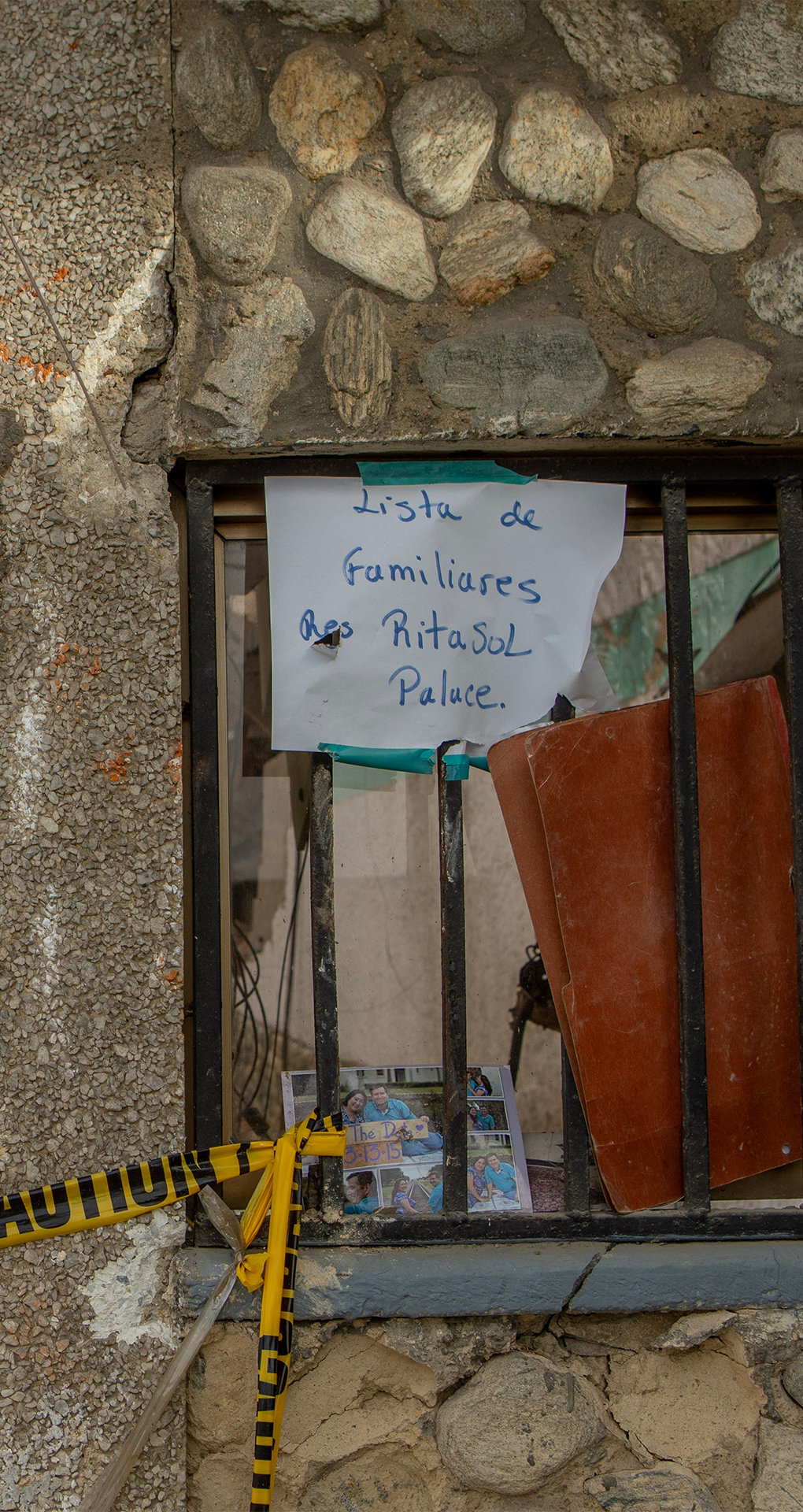 A sign reads ‘List of family members Ritasol Palace’ [Alfie Pannell/Al Jazeera]