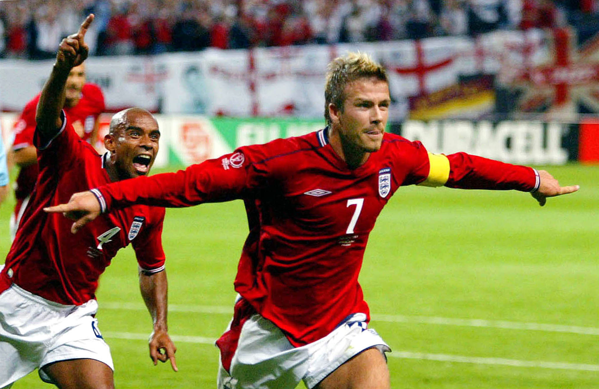 England captain David Beckham (R) runs in celebration with team mate Trevor Sinclair after scoring from the penalty spot against Argentina