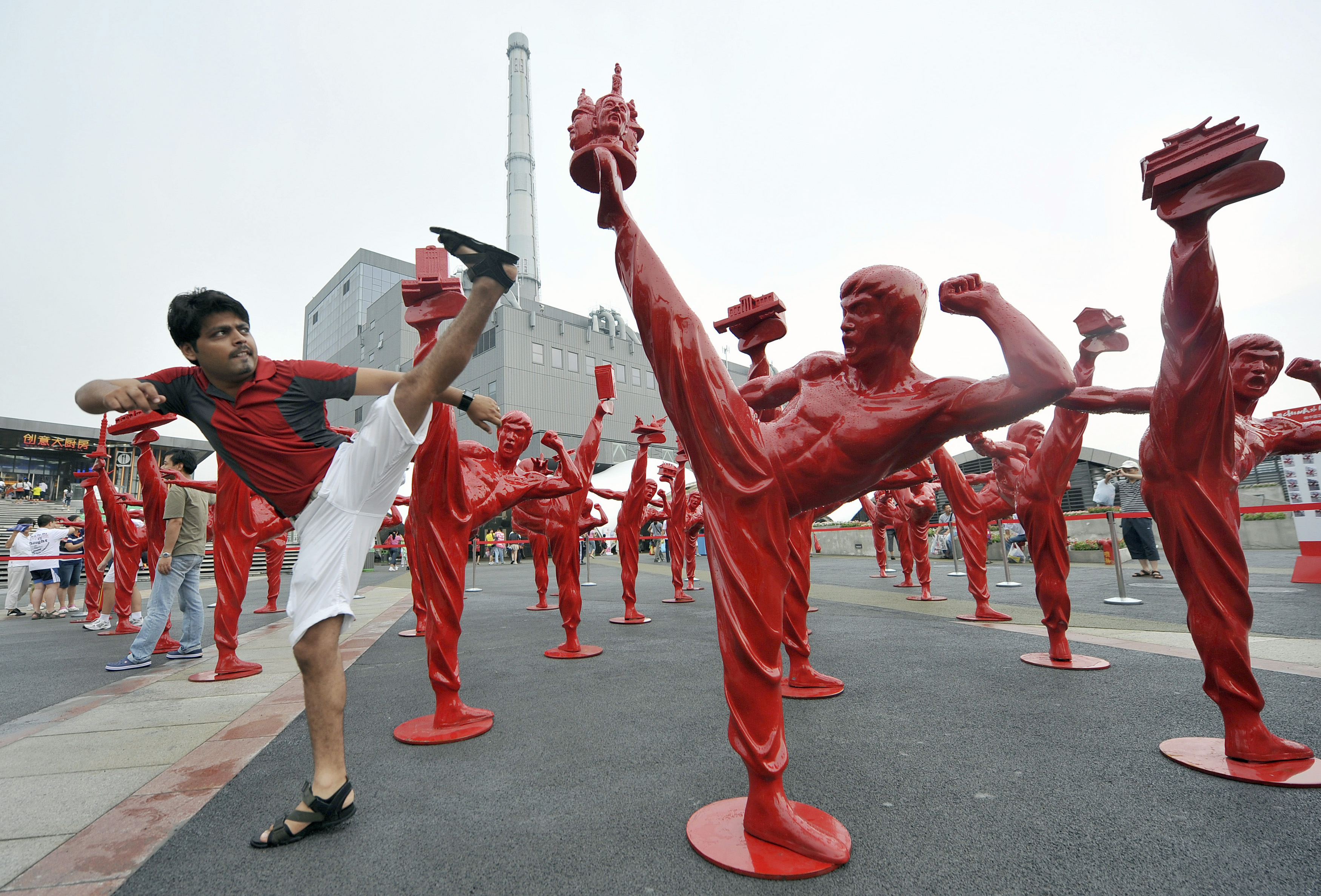 An Indian tourist poses next to statues of Bruce Lee during an exhibition at the Shanghai World Expo site, August 18, 2010. REUTERS/Stringer (CHINA - Tags: TRAVEL SOCIETY) CHINA OUT. NO COMMERCIAL OR EDITORIAL SALES IN CHINA