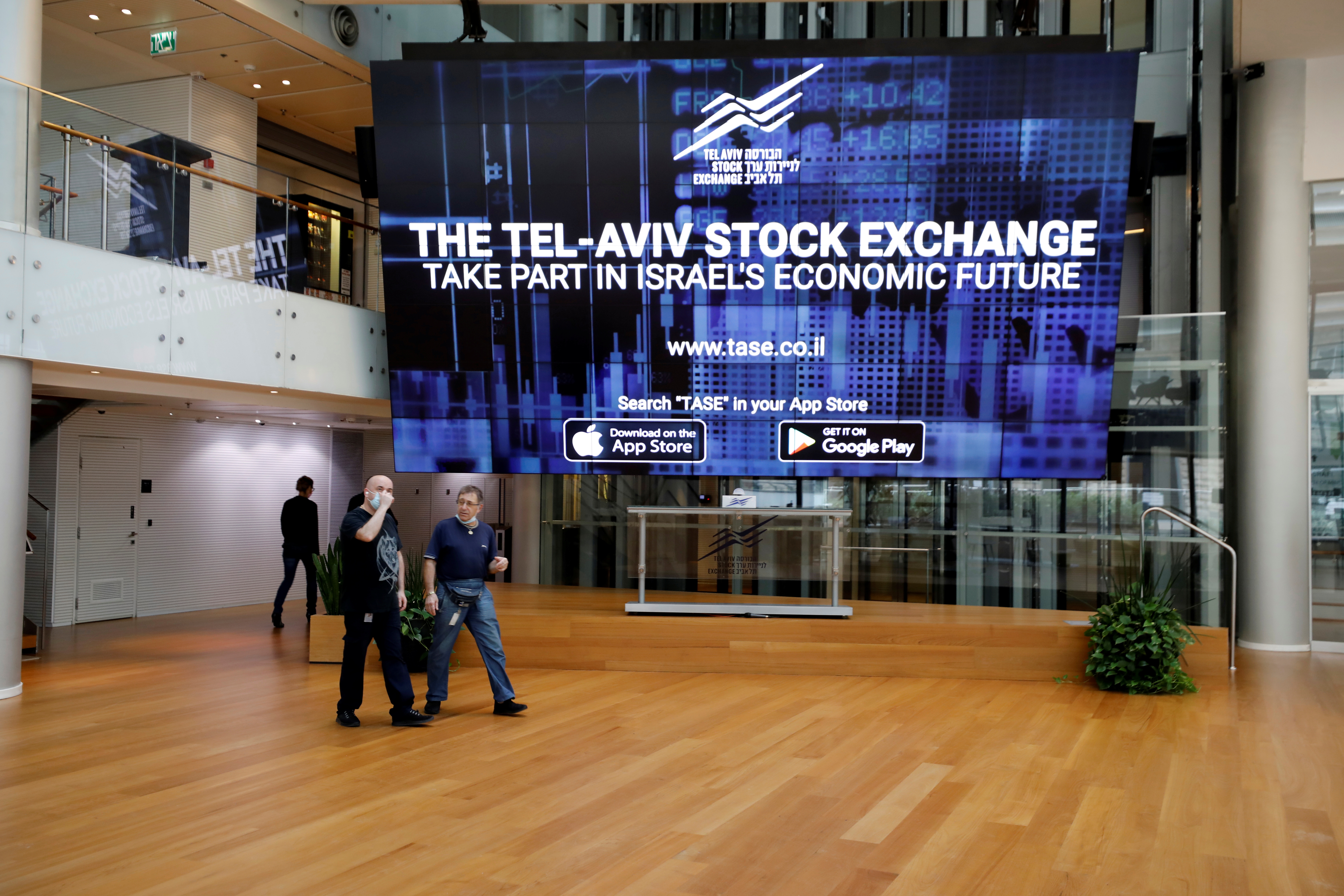 Men walk past an electronic board at the Tel Aviv Stock Exchange, in Tel Aviv, Israel November 4, 2020. Picture taken November 4, 2020. REUTERS/Amir Cohen