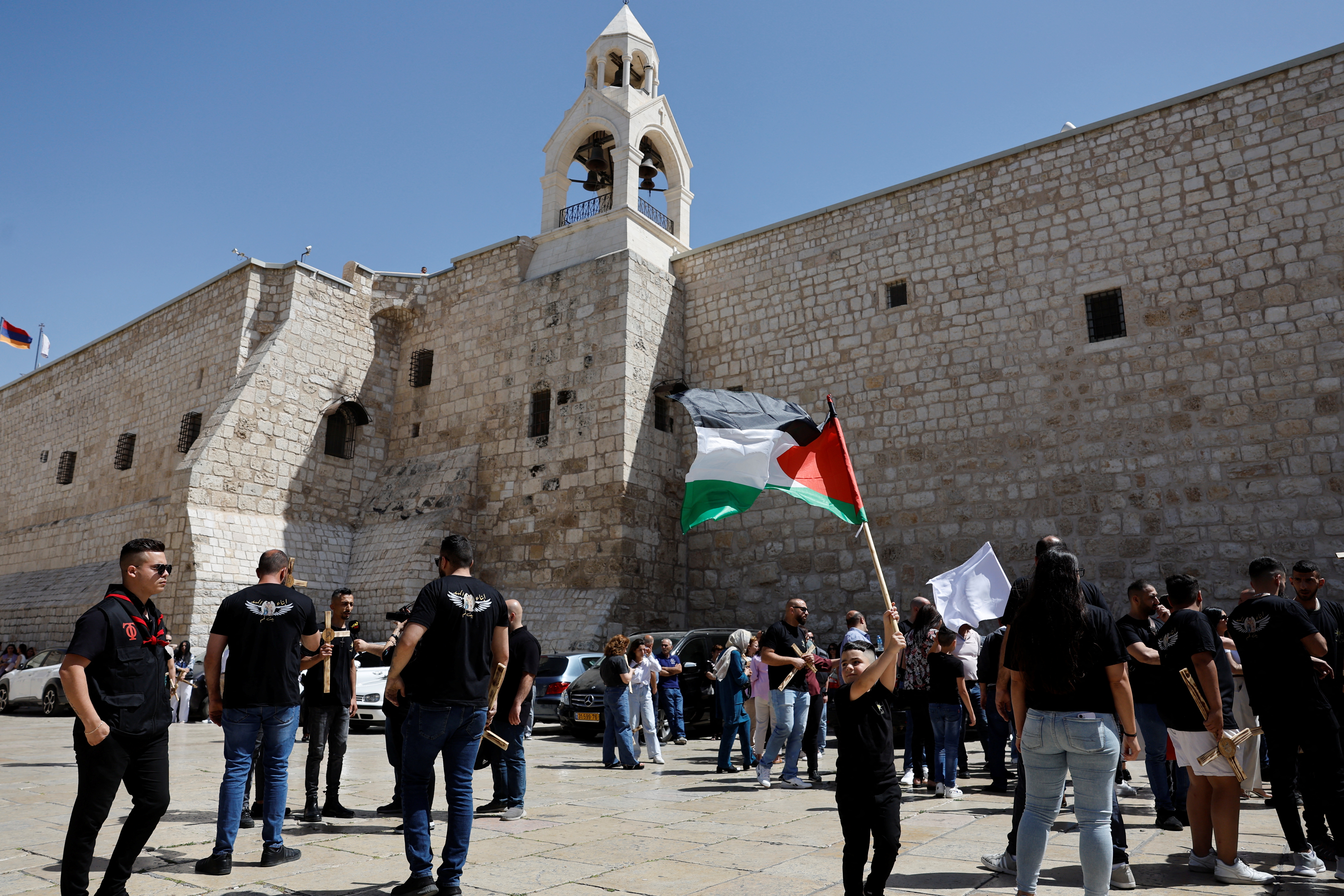 A child holds a Palestinian flag outside the Church of Nativity, on the day the Holy Fire arrives in Bethlehem, in the Israeli-occupied West Bank, May 4, 2024. REUTERS/Mussa Qawasma
