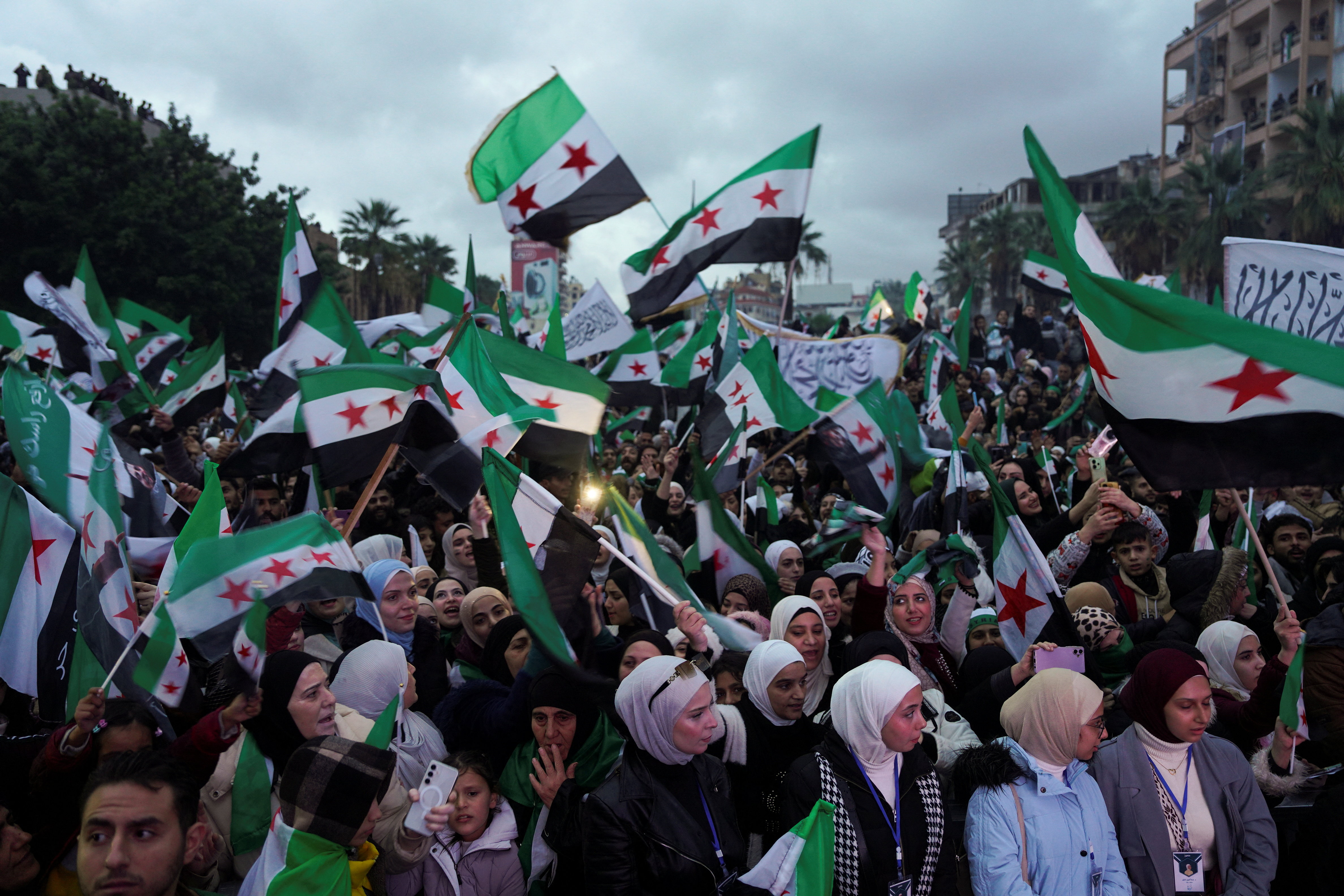 Syrians holds flags as they gather to mark the first anniversary of Bashar al-Assad's fall, in Latakia, Syria December 8, 2025. REUTERS/Karam al-Masri