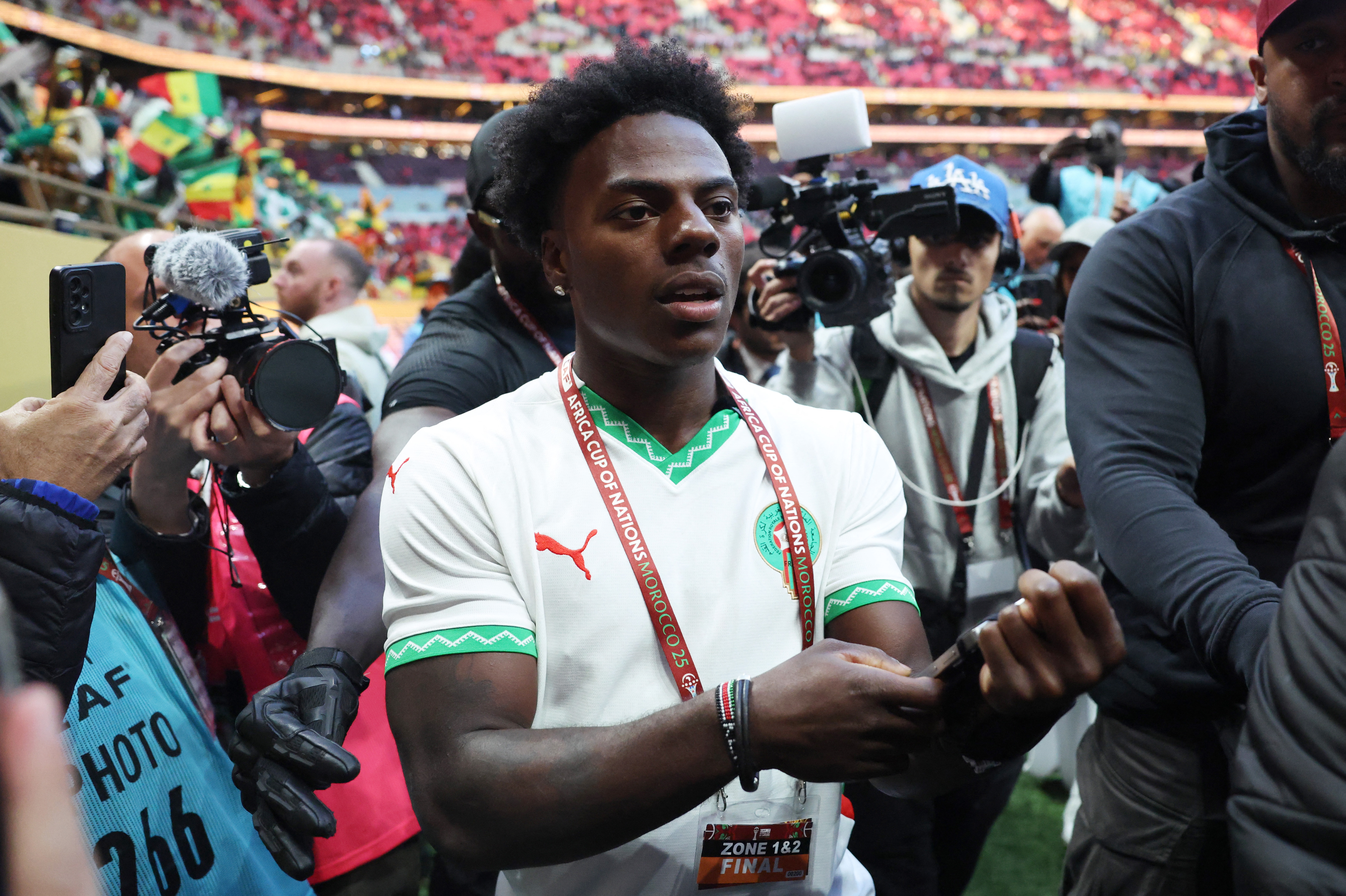 IShowSpeed holds up a phone on a selfie stick as he films himself in the stands of a packed stadium