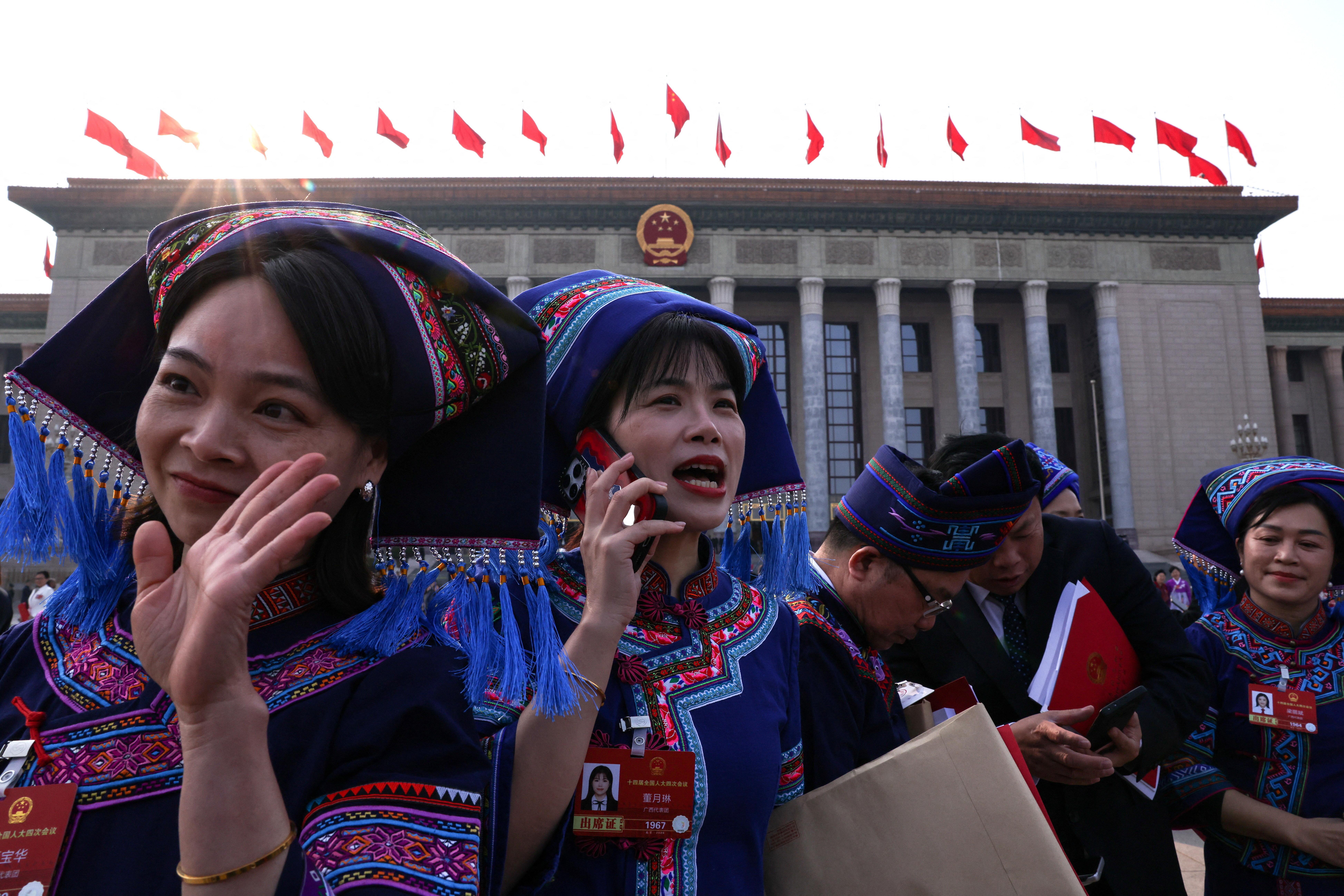 Delegates in ethnic minority costumes hold documents as they leave following the closing session of the National People's Congress (NPC) at the Great Hall of the People in Beijing, China