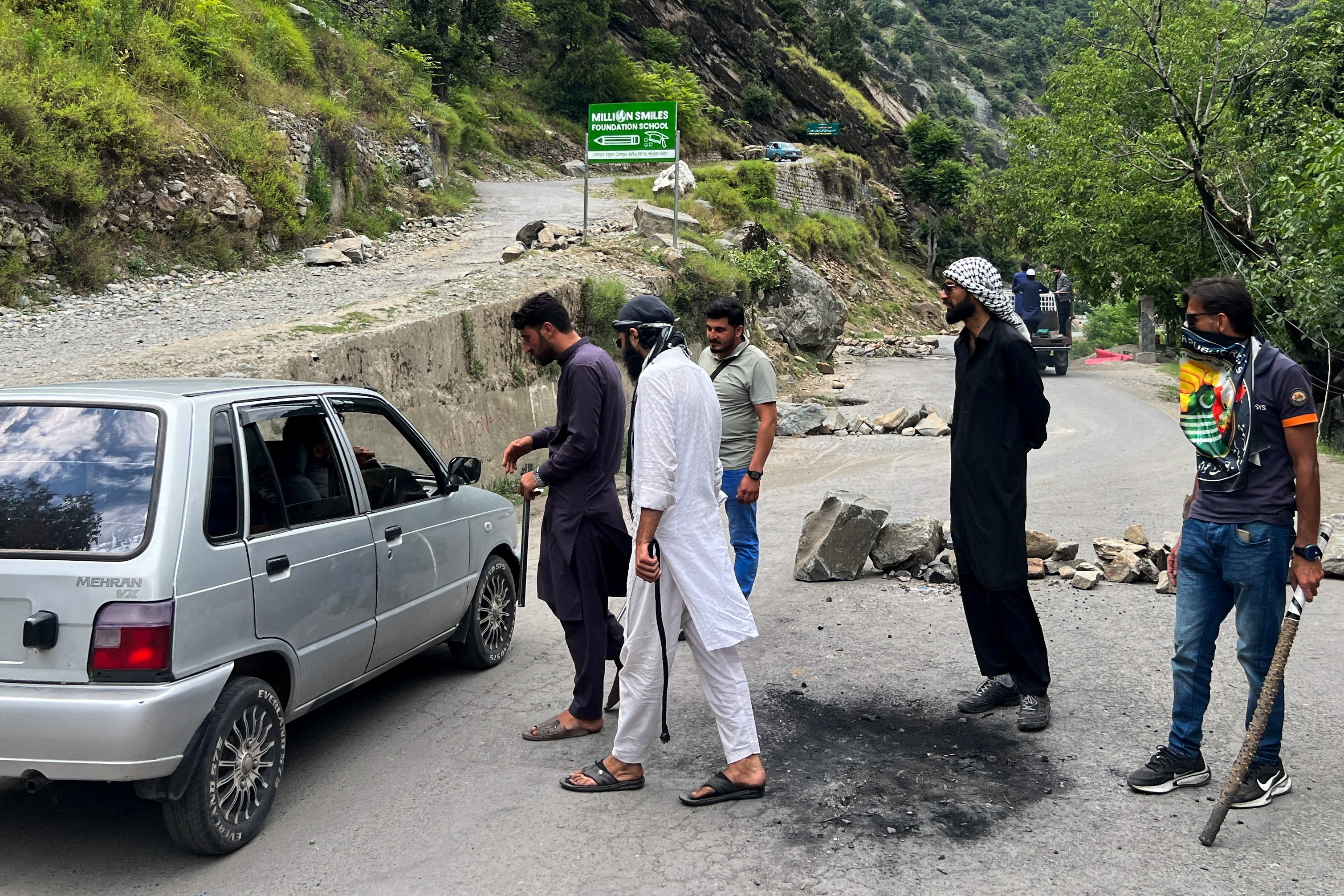People approach a vehicle at a mekeshift check point during a protest and shutter-down strike called by the banned Joint Awami Action Committee (JAAC), an alliance of civil society groups, in Neelum Valley, Pakistani Kashmir, June 21, 2026. Picture taken with a mobile phone. REUTERS/Naseer ud Din