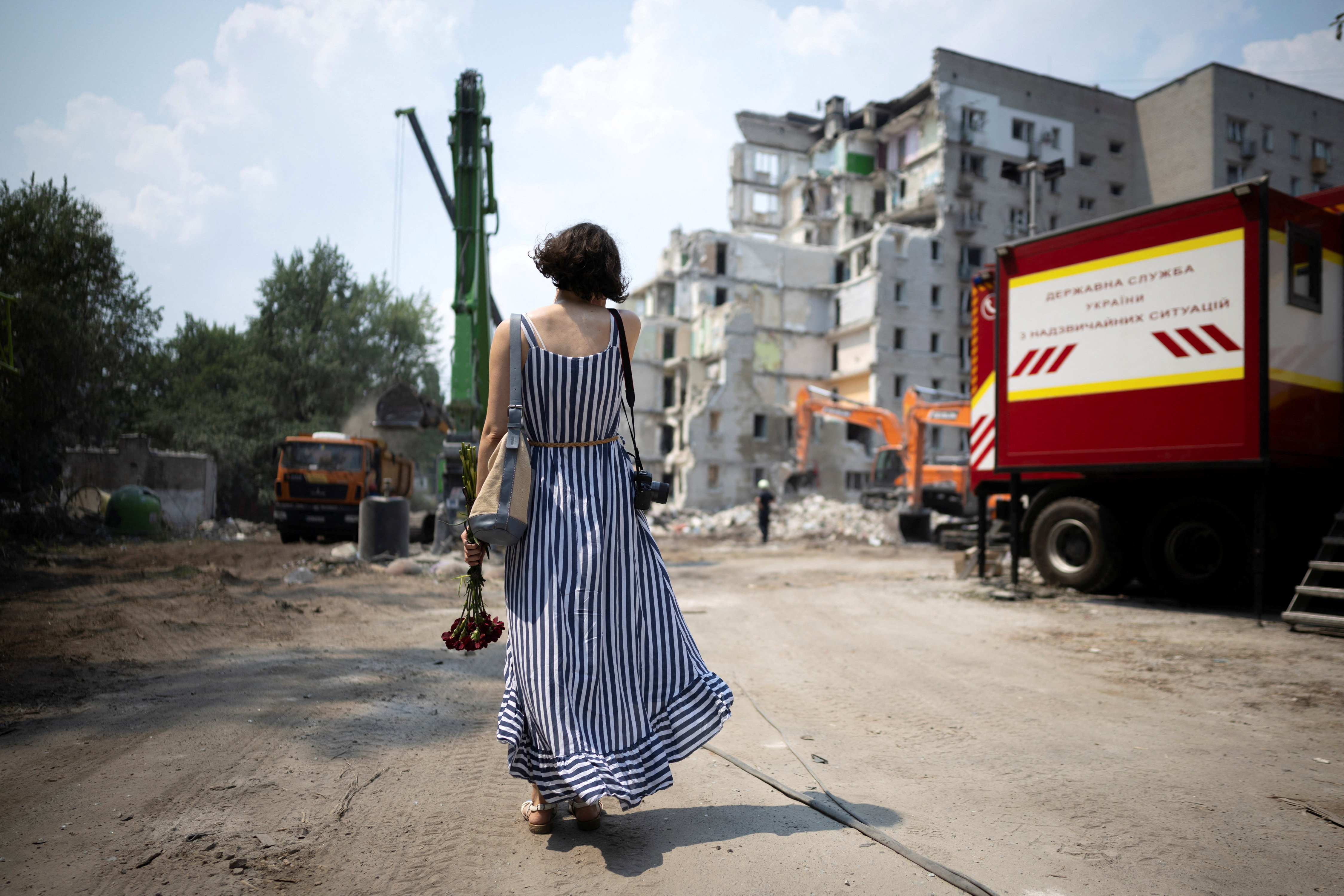 A woman holding flowers looks at an apartment building that was hit during Thursday’s Russian missile and drone attacks, amid Russia's attack on Ukraine, in Kyiv, Ukraine, July 3, 2026. REUTERS/Thomas Peter TPX IMAGES OF THE DAY