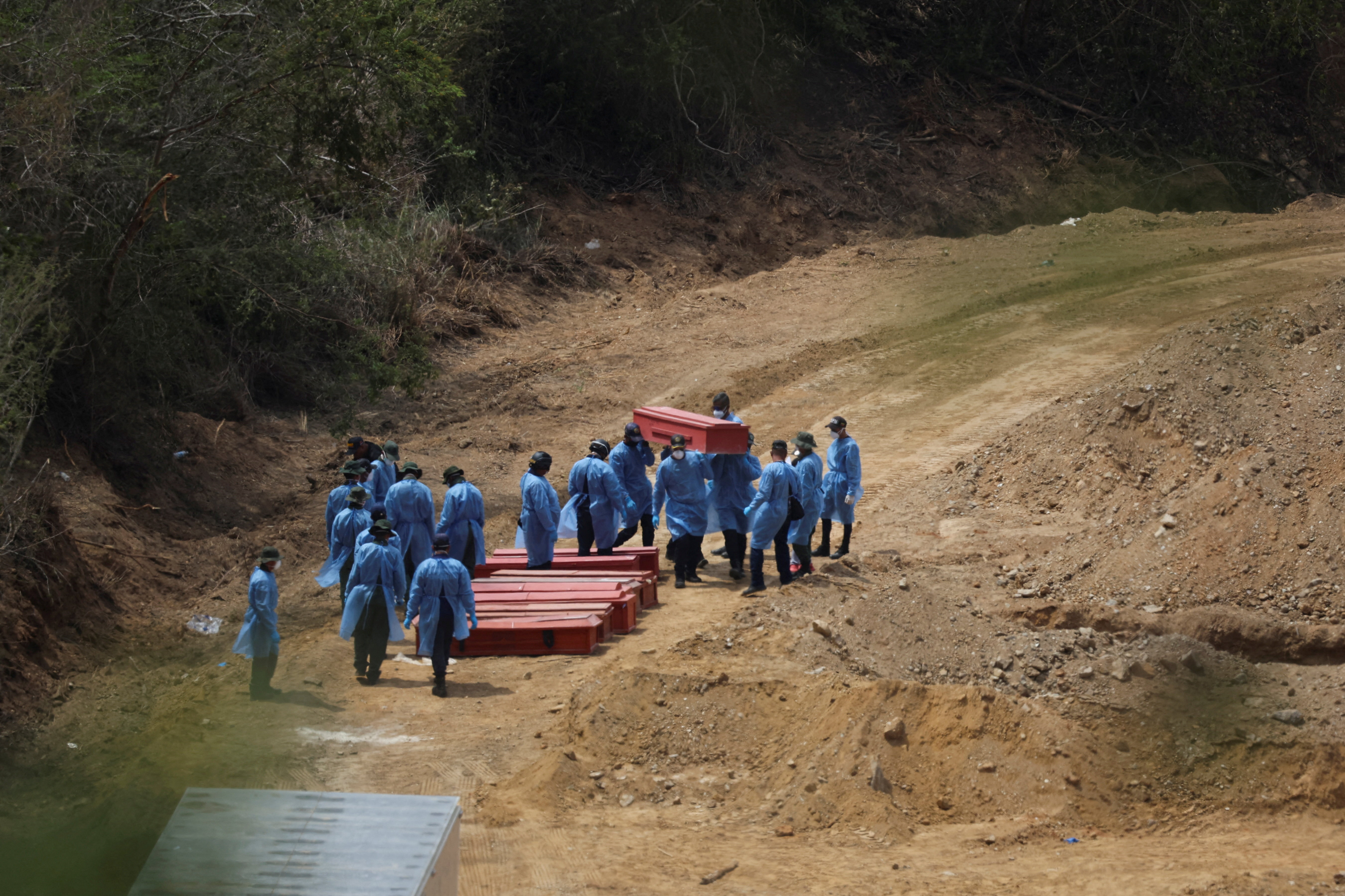 Workers carry a coffin of an earthquake victim next to other coffins at La Esperanza Cemetery in the aftermath of the June 24 earthquakes, in La Guaira, Venezuela [Adriano Machado/Reuters]