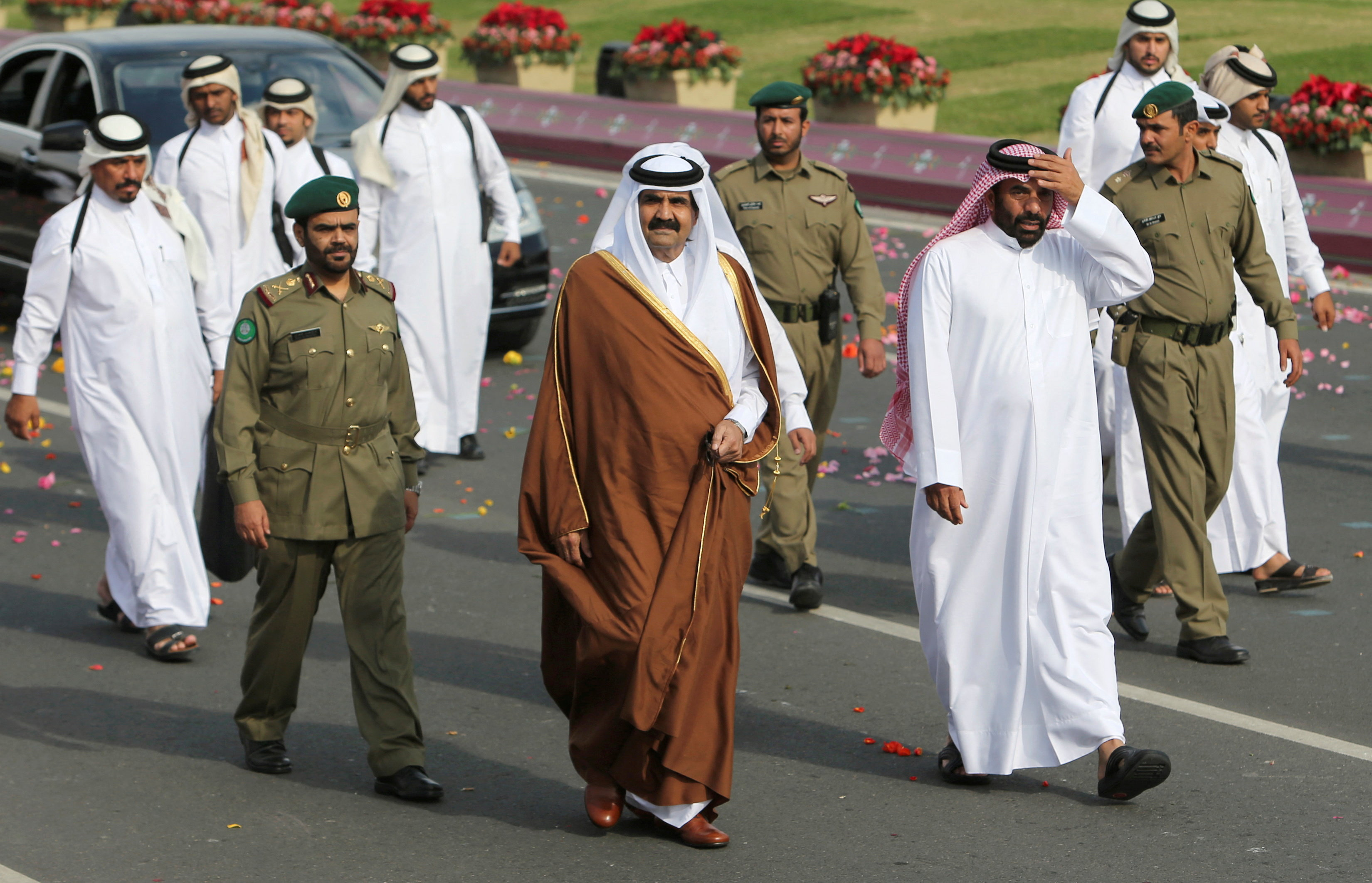 Sheikh Hamad walks beside members of a security team as he arrives to attend the National Day celebrations in Doha, Qatar