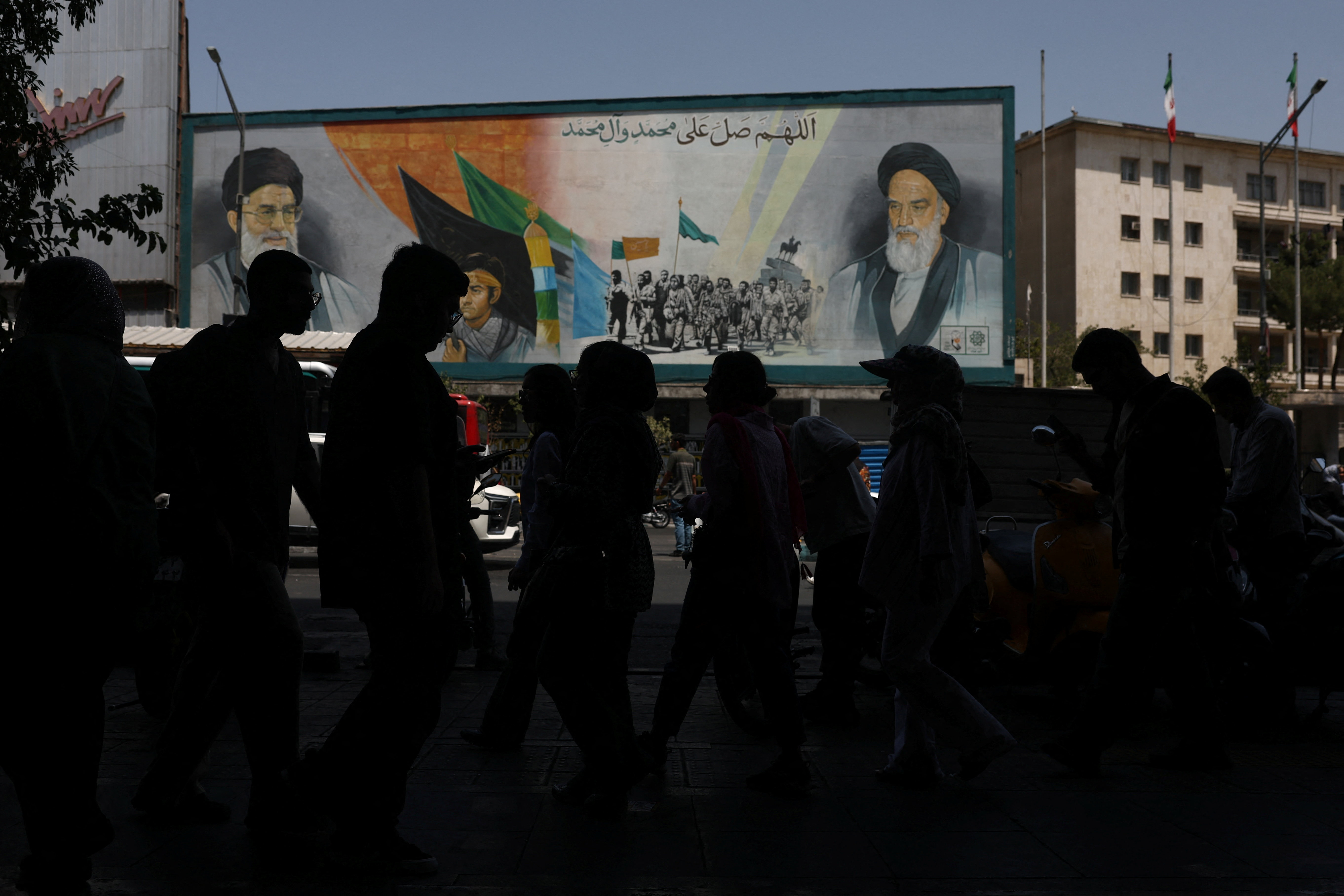 People walk past a mural depicting the late leader of the Islamic Revolution, Ayatollah Ruhollah Khomeini, and Iran's late Supreme Leader Ayatollah Ali Khamenei, on a street in Tehran, Iran, July 15, 2026. Majid Asgaripour/WANA (West Asia News Agency) via REUTERS ATTENTION EDITORS - THIS PICTURE WAS PROVIDED BY A THIRD PARTY. ISRAEL OUT. NO COMMERCIAL OR EDITORIAL SALES IN ISRAEL. NO ACCESS FOR ISRAELI MEDIA. NO USE BBC PERSIAN. NO USE VOA PERSIAN. NO USE MANOTO. NO USE IRAN INTERNATIONAL. NO USE RADIO FARDA. DIGITAL: NO USE BBC PERSIAN. NO USE VOA PERSIAN. NO USE MANOTO. NO USE IRAN INTERNATIONAL. NO USE RADIO FARDA.