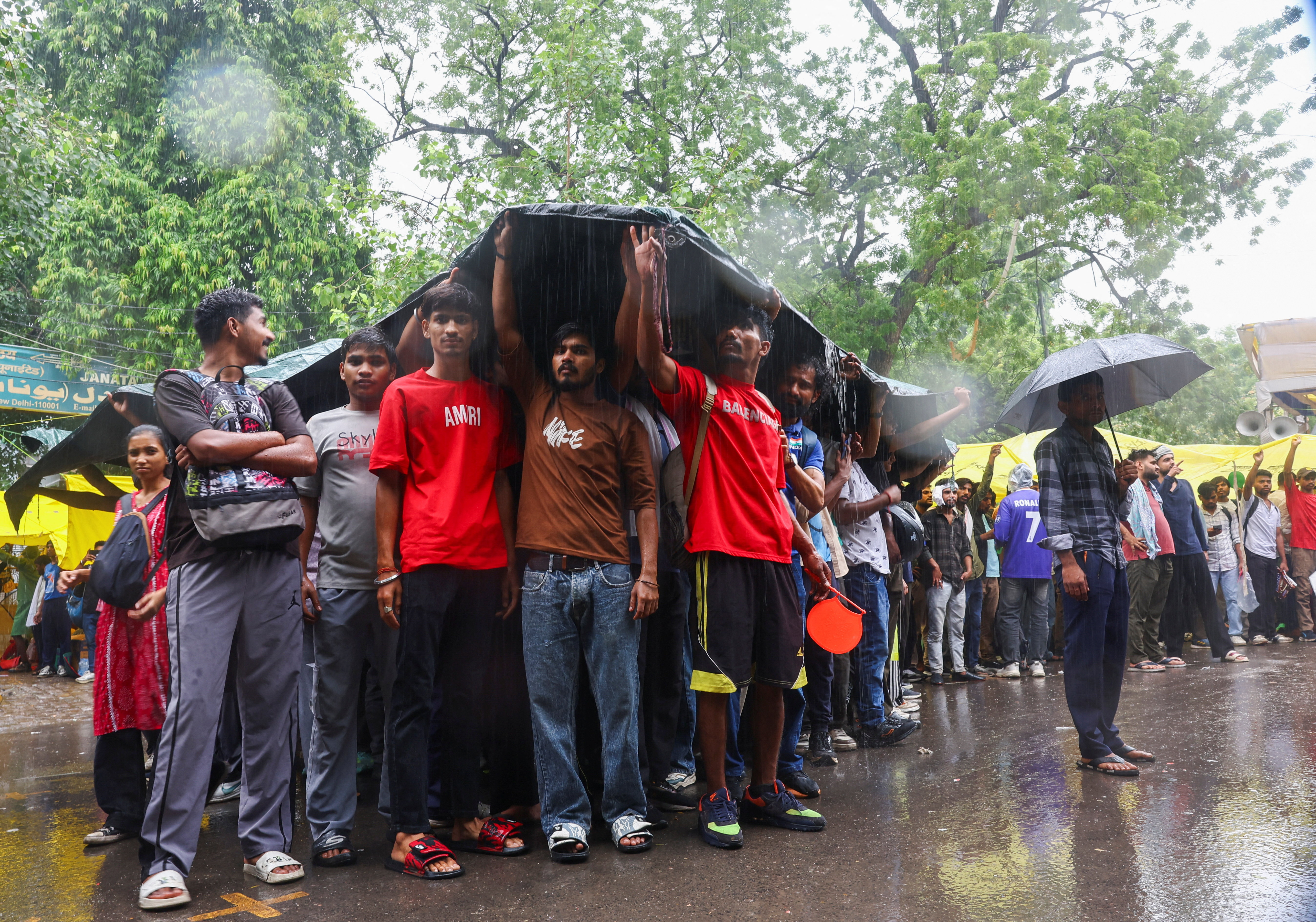 Supporters of India’s Cockroach Janta Party (CJP) take shelter at a protest site, two days after thousands of protesters marched towards parliament demanding the resignation of Education Minister Dharmendra Pradhan over examination paper leaks, at Jantar Mantar in New Delhi, India, on July 22, 2026